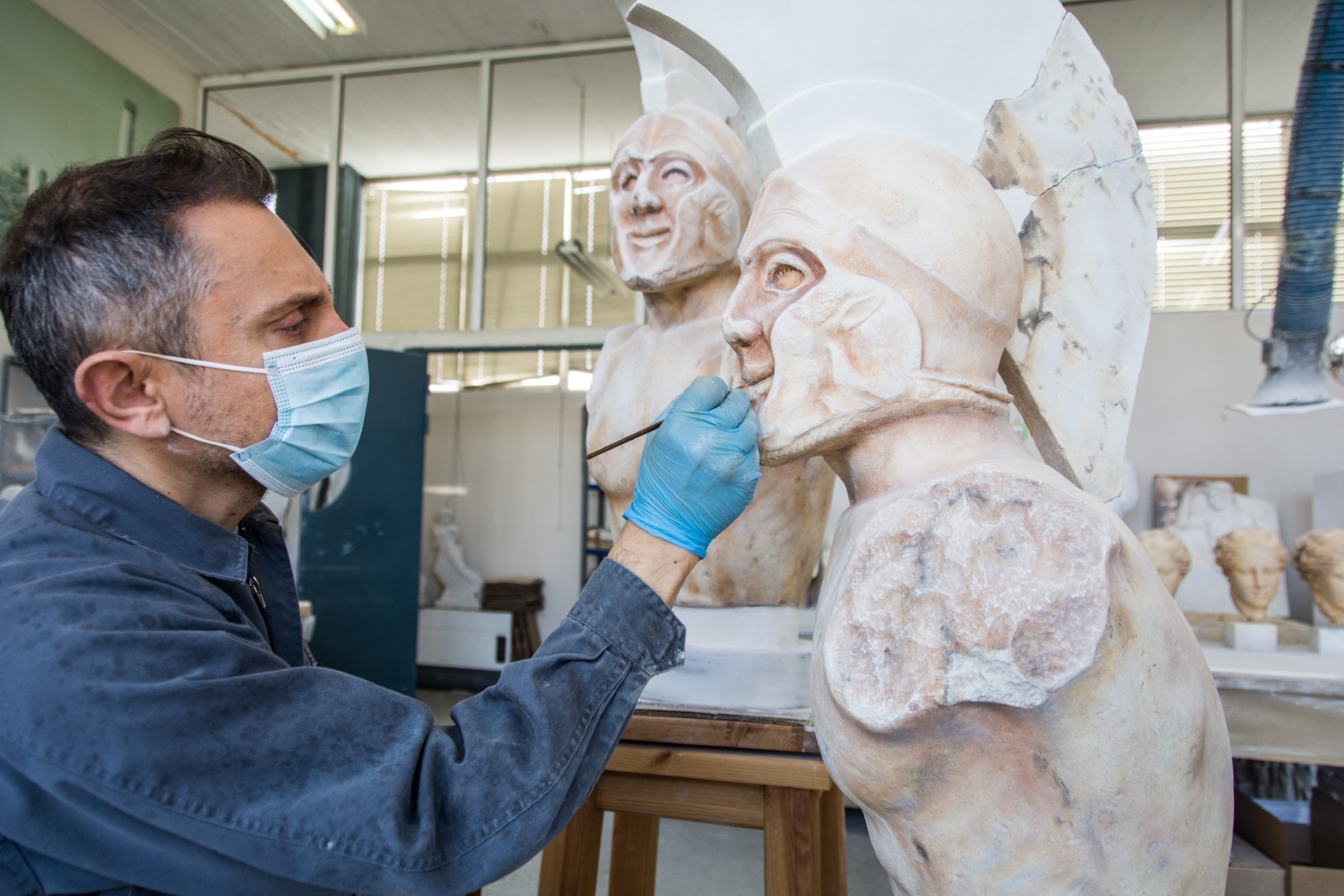 A painter adds imperfections to a newly made statue to match the original creation found in ruins.