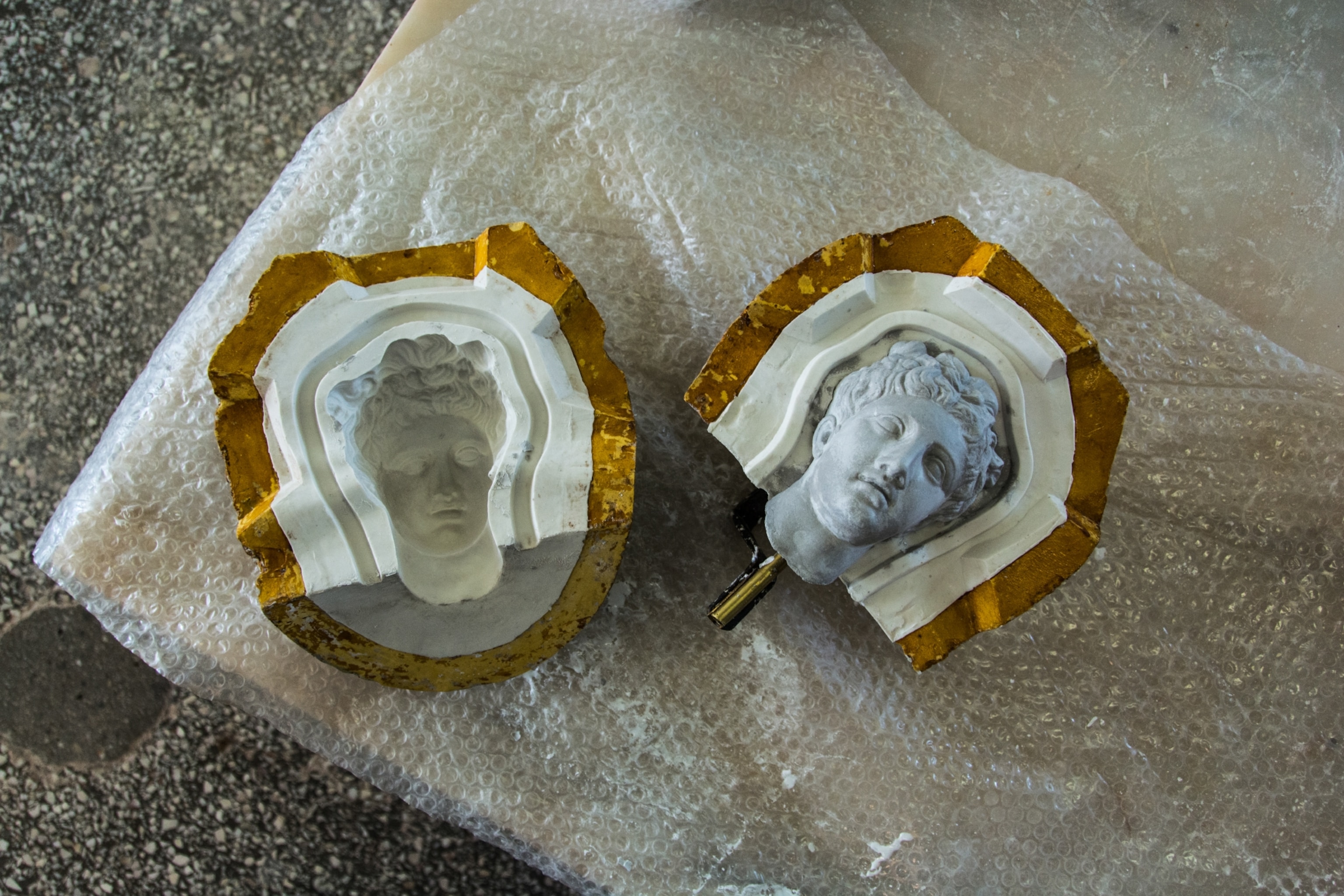 The face of a statue lays next to the case that gave it form