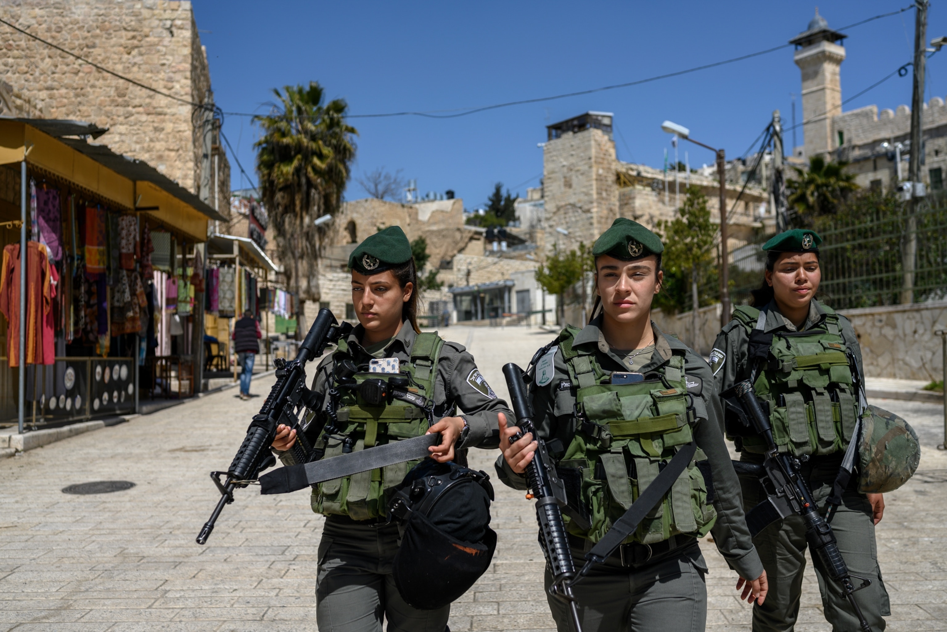three armed women walking down the street in West Bank