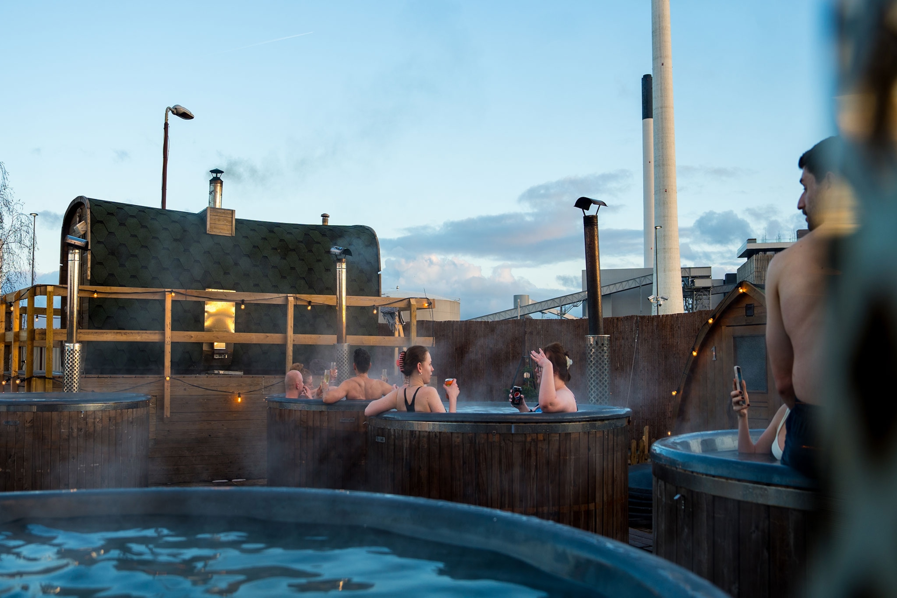 People drink and chat while sitting in outdoor baths in Copenhagen.