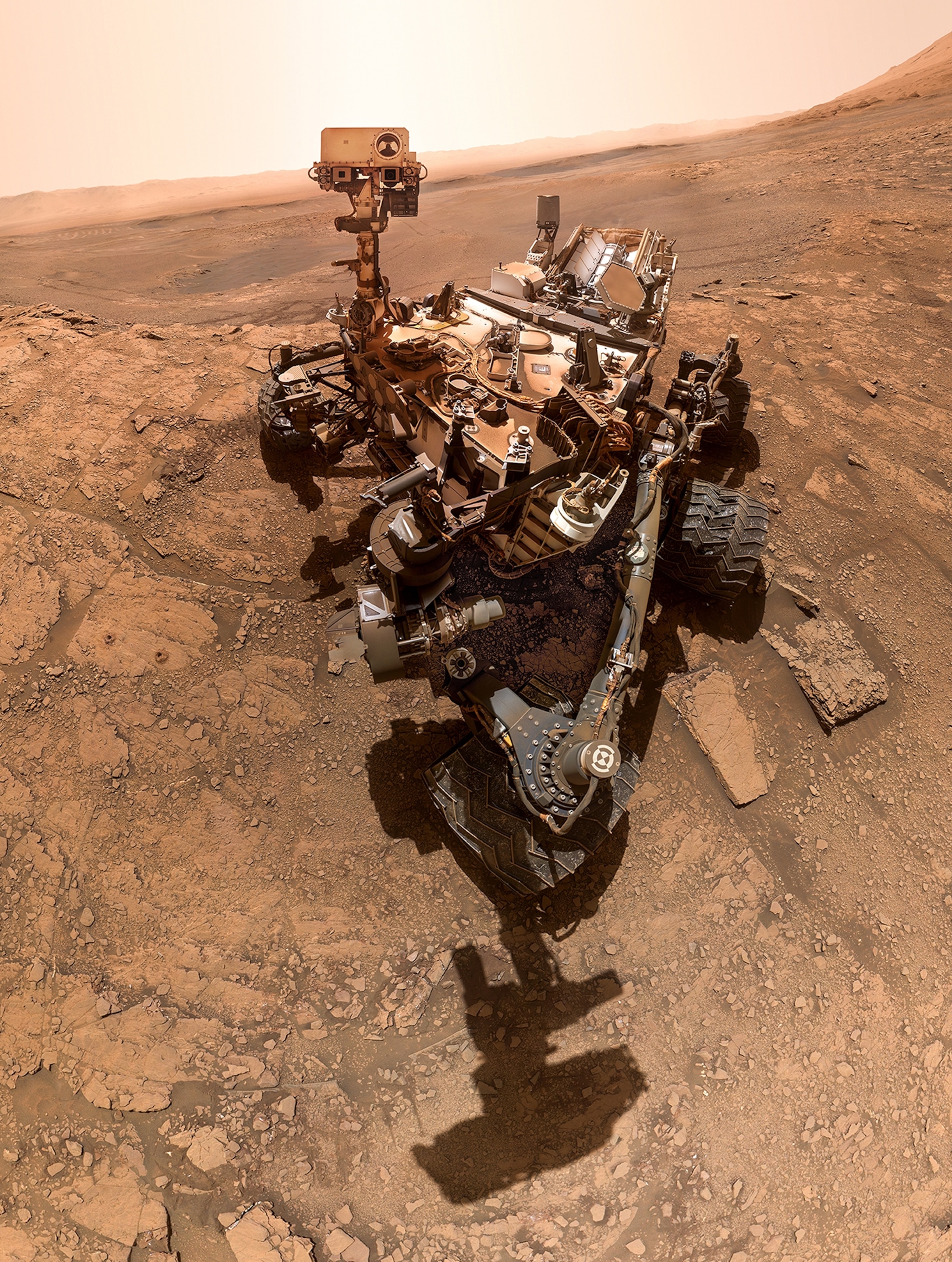 Mars rover on light-brown rocky surface.
