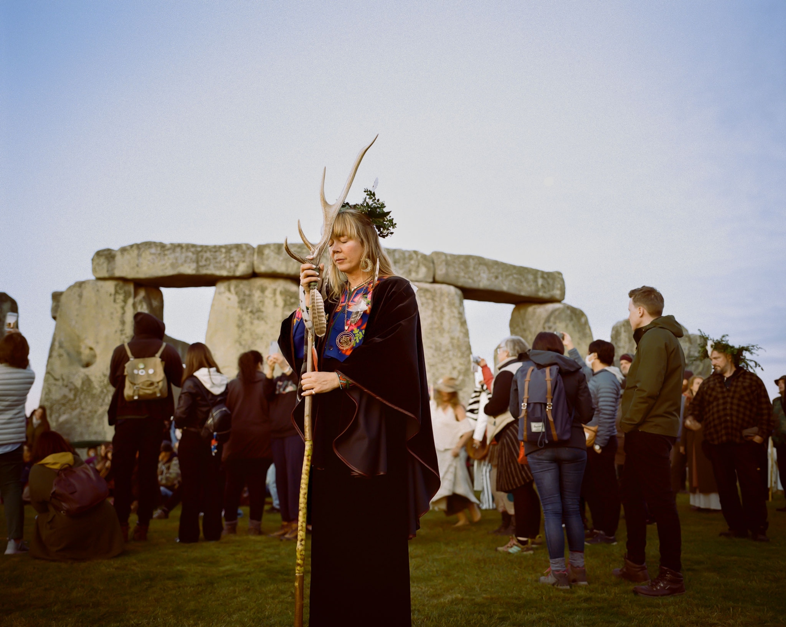 a woman presses her staff to her forehead during the autumn equinox at Stonehenge