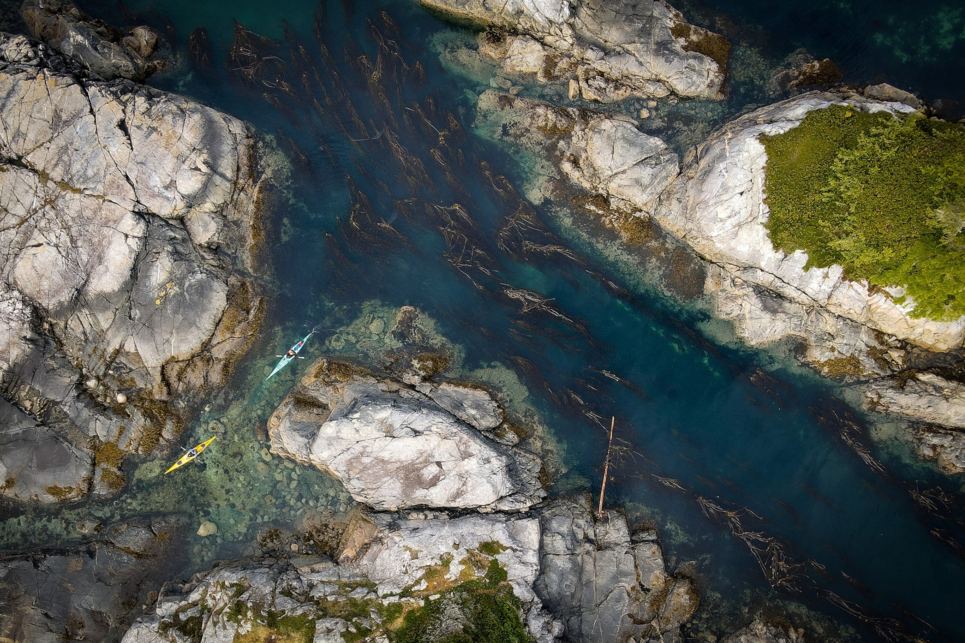 Arial shot of sea kayakers weaving their way through rocks in British Colombia.