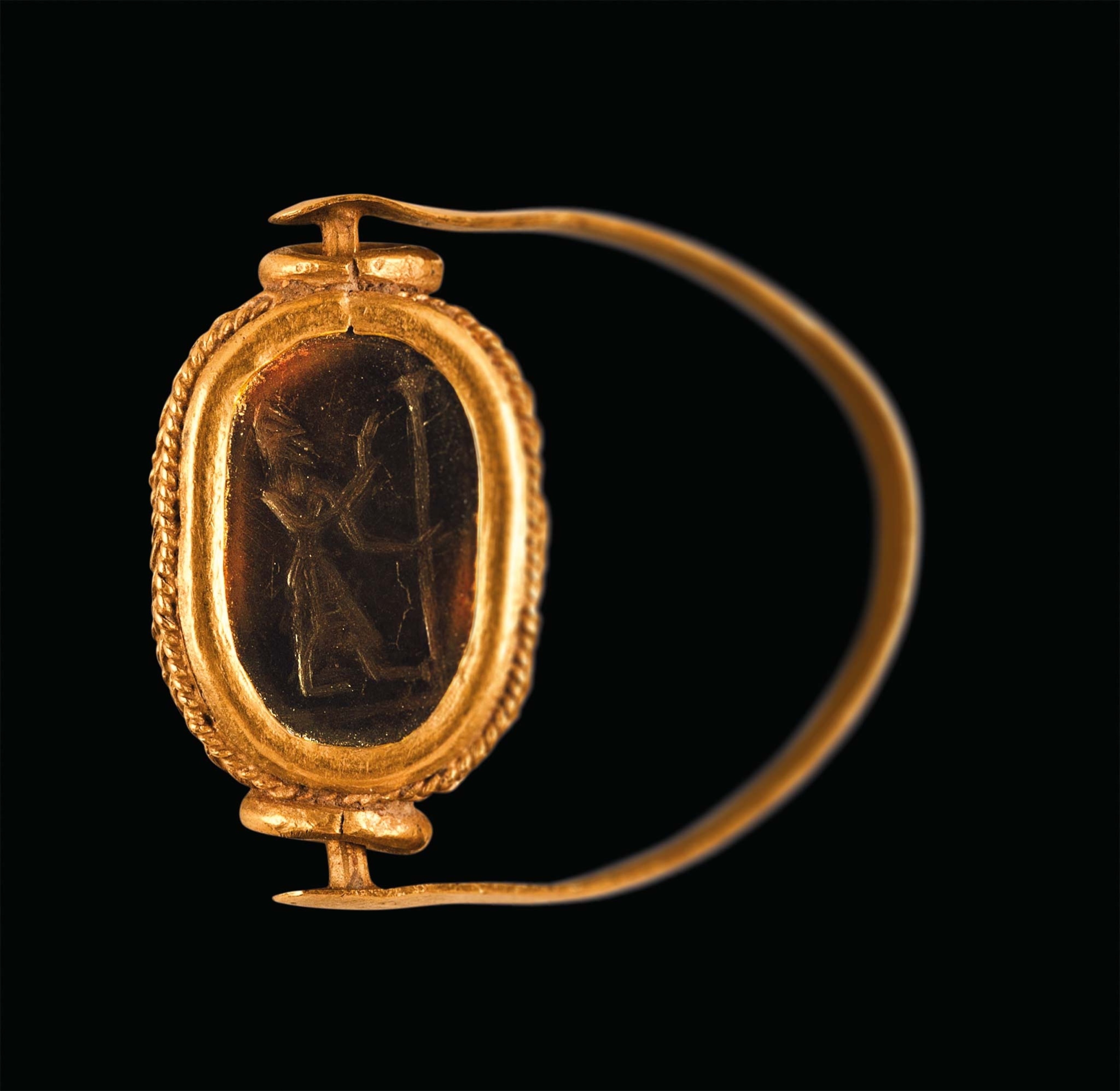 A gold and jasper ring is engraved with a bearded figure with a scepter in his hand