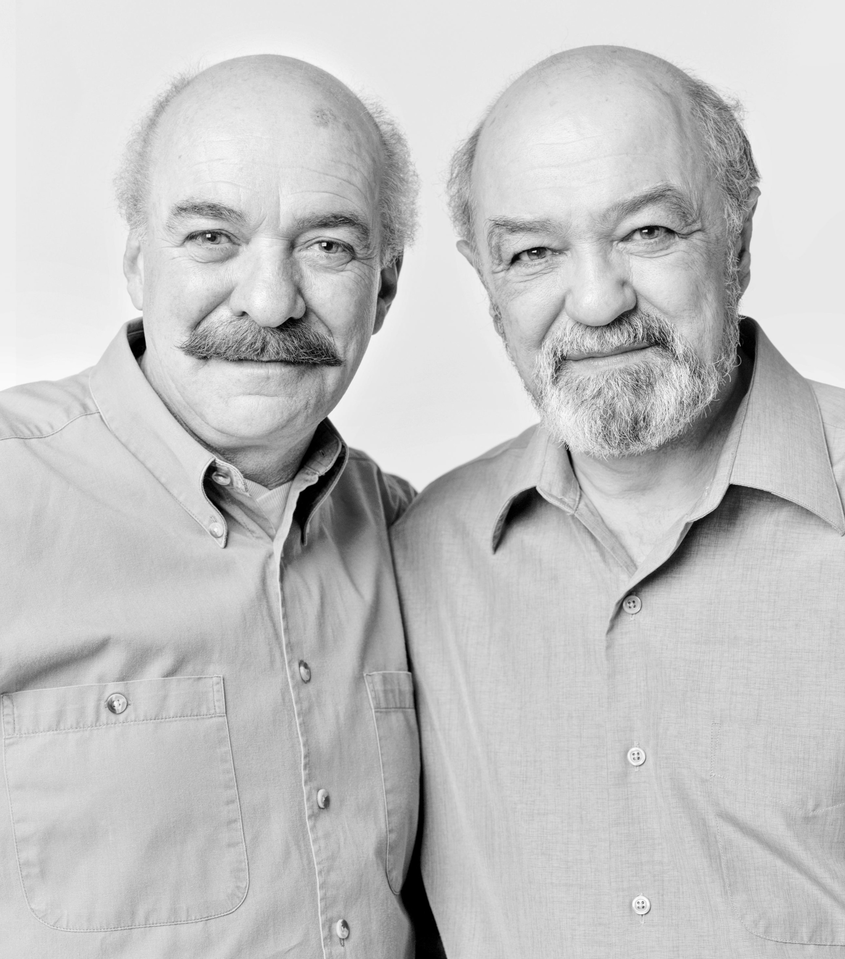 Head-and-shoulders portrait of two bald, middle-aged white men who resemble each other closely