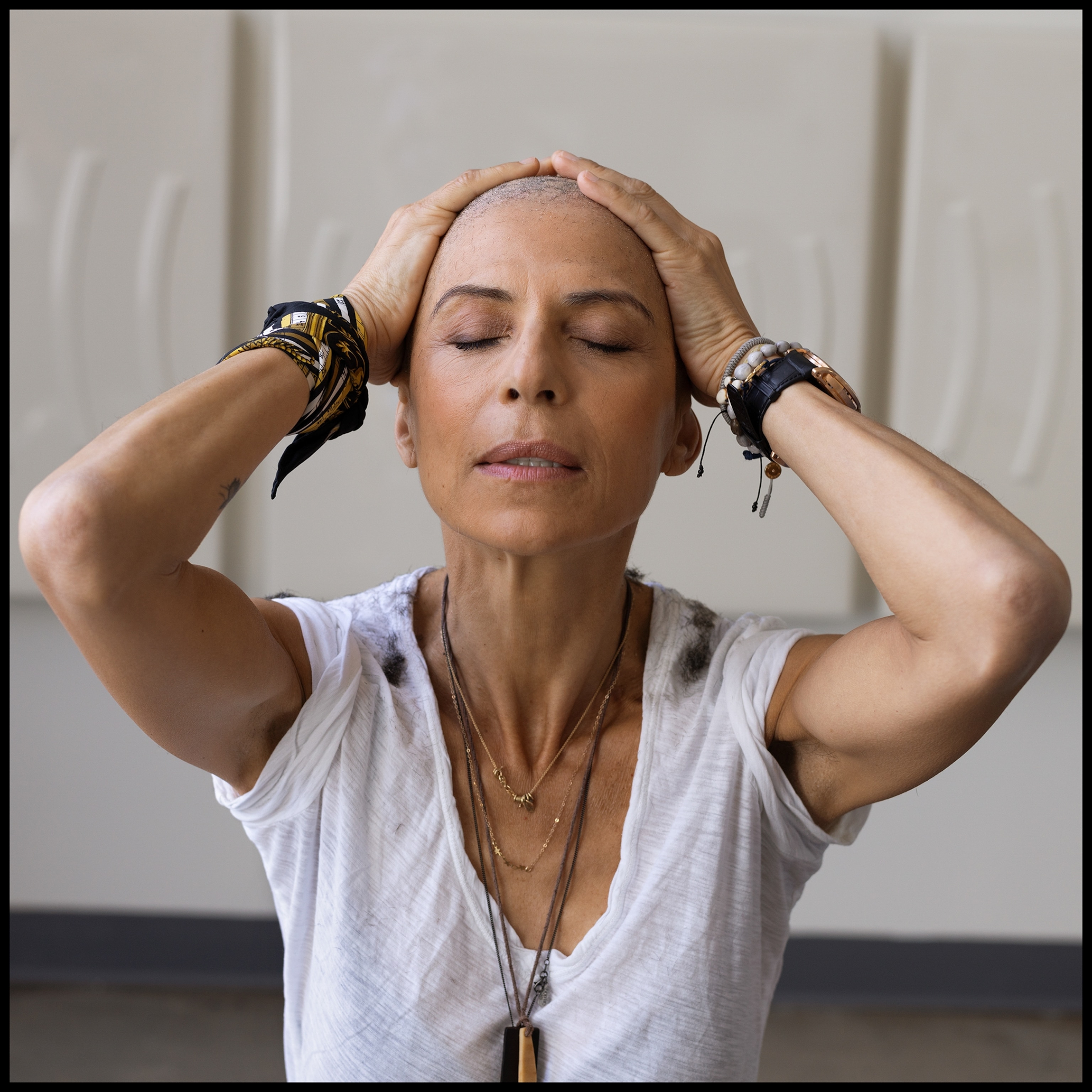 a woman with her eyes closed and hands on her head