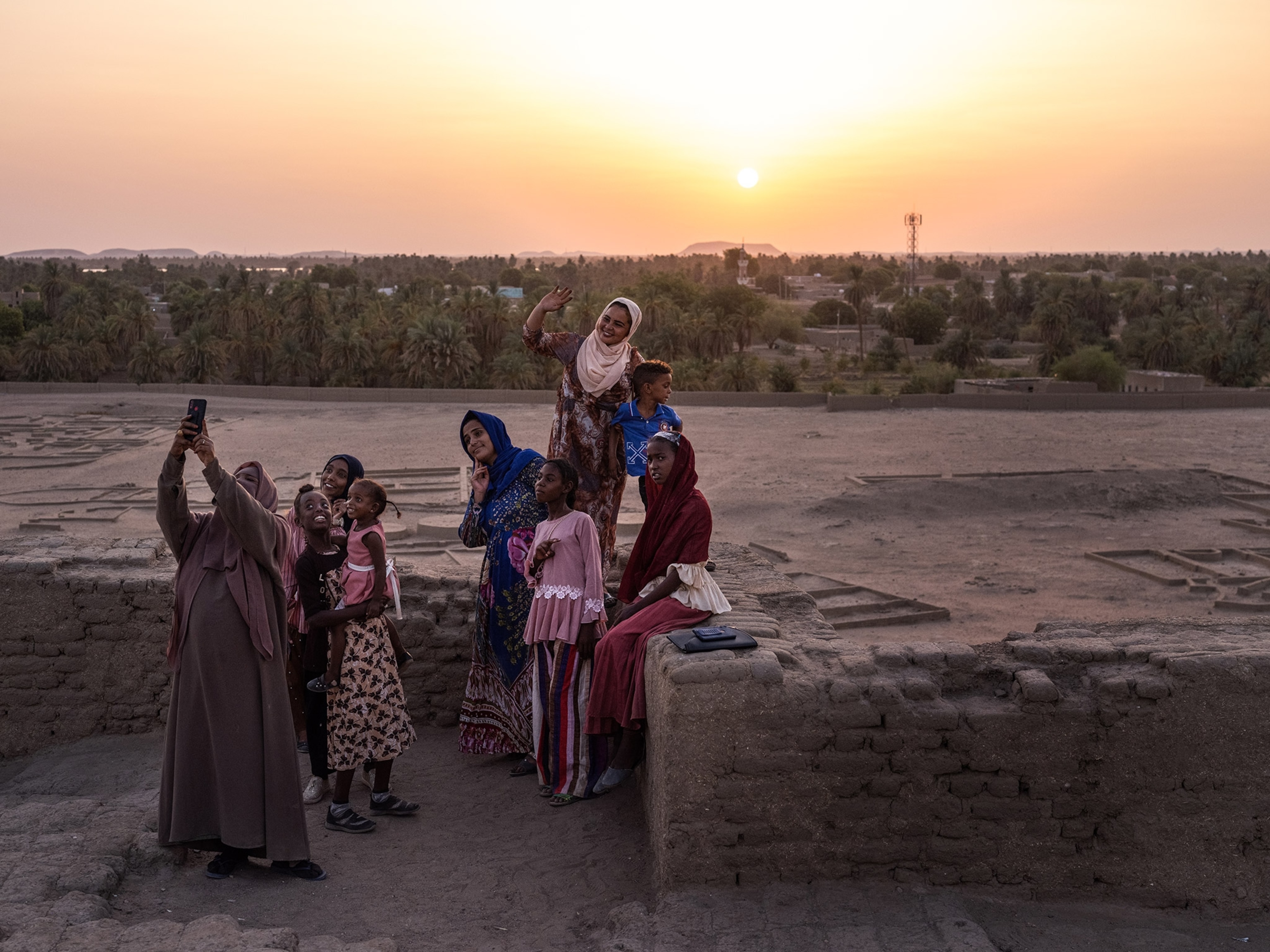 Tahani Abdulaziz take a photograph of Nuha Awad and other family members during a visit to the ancient city of Kerma, Sudan