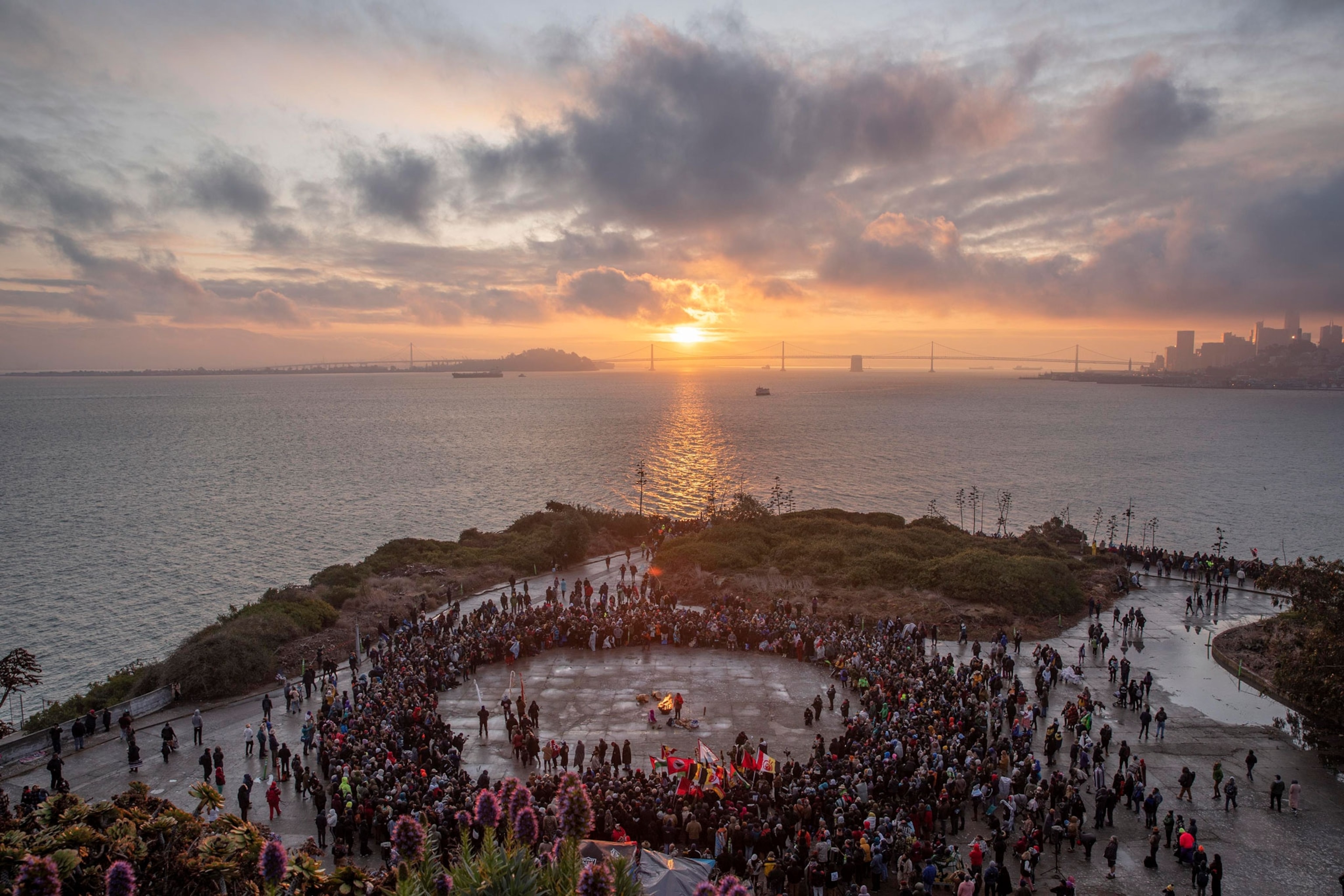 People gather near the ocean at sunrise
