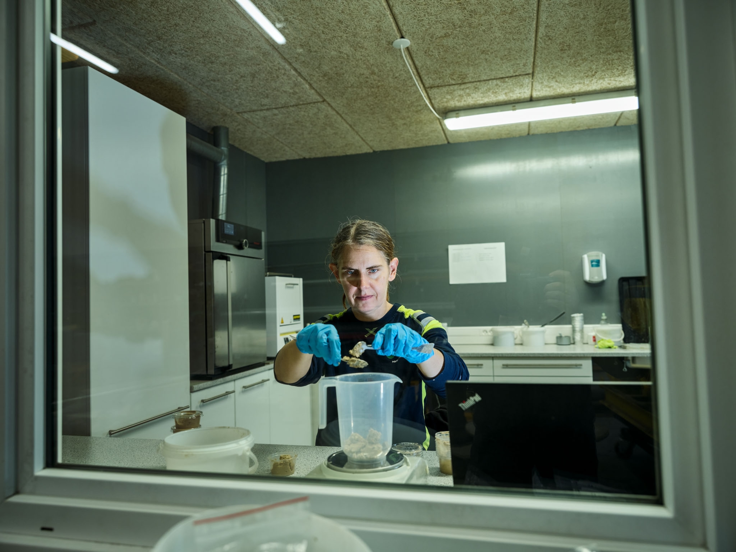 a woman in a lab placing bio material into a container on a scale