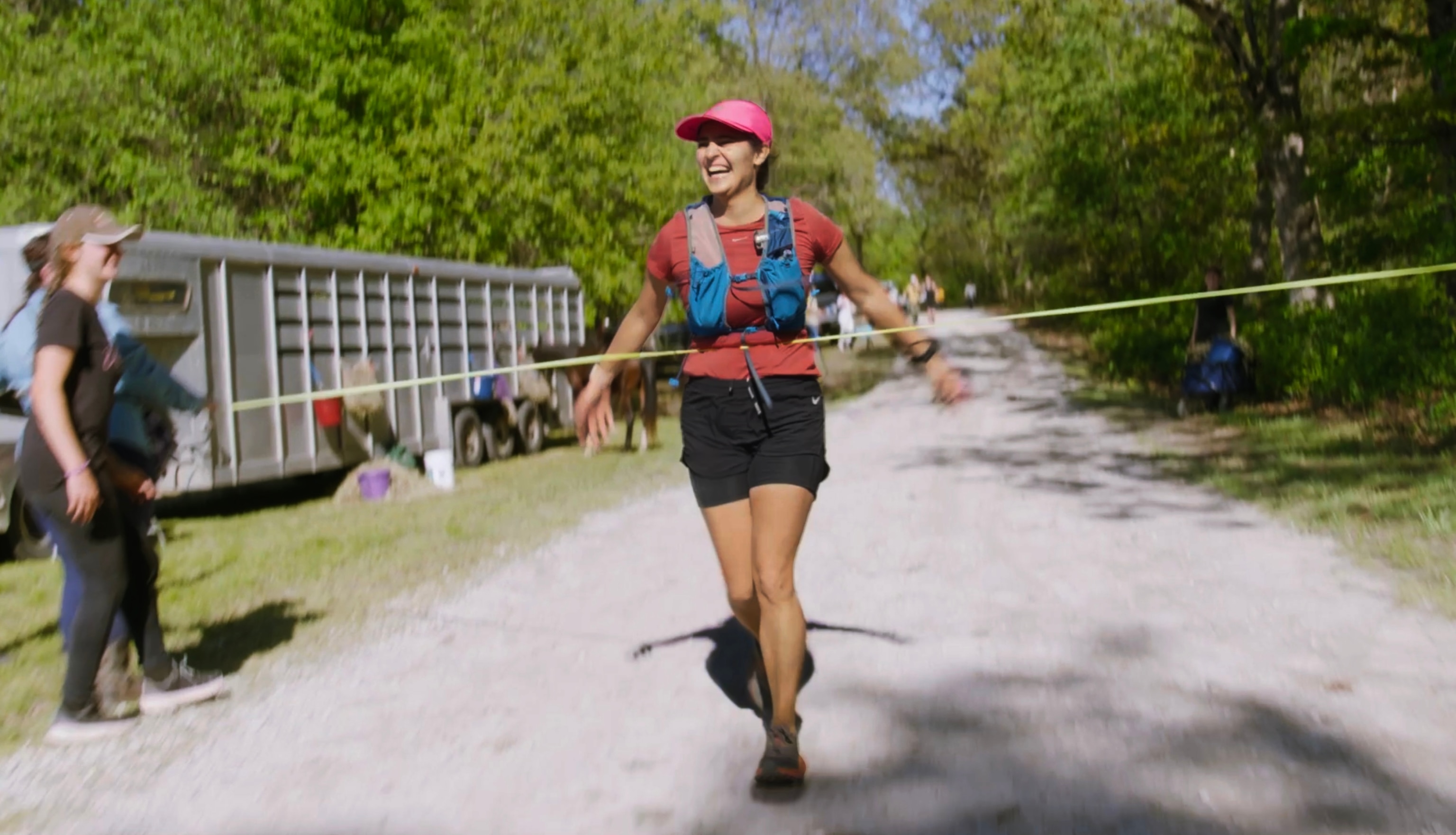 A woman runs a race on a gravel road, crossing the finish line and winning the race.
