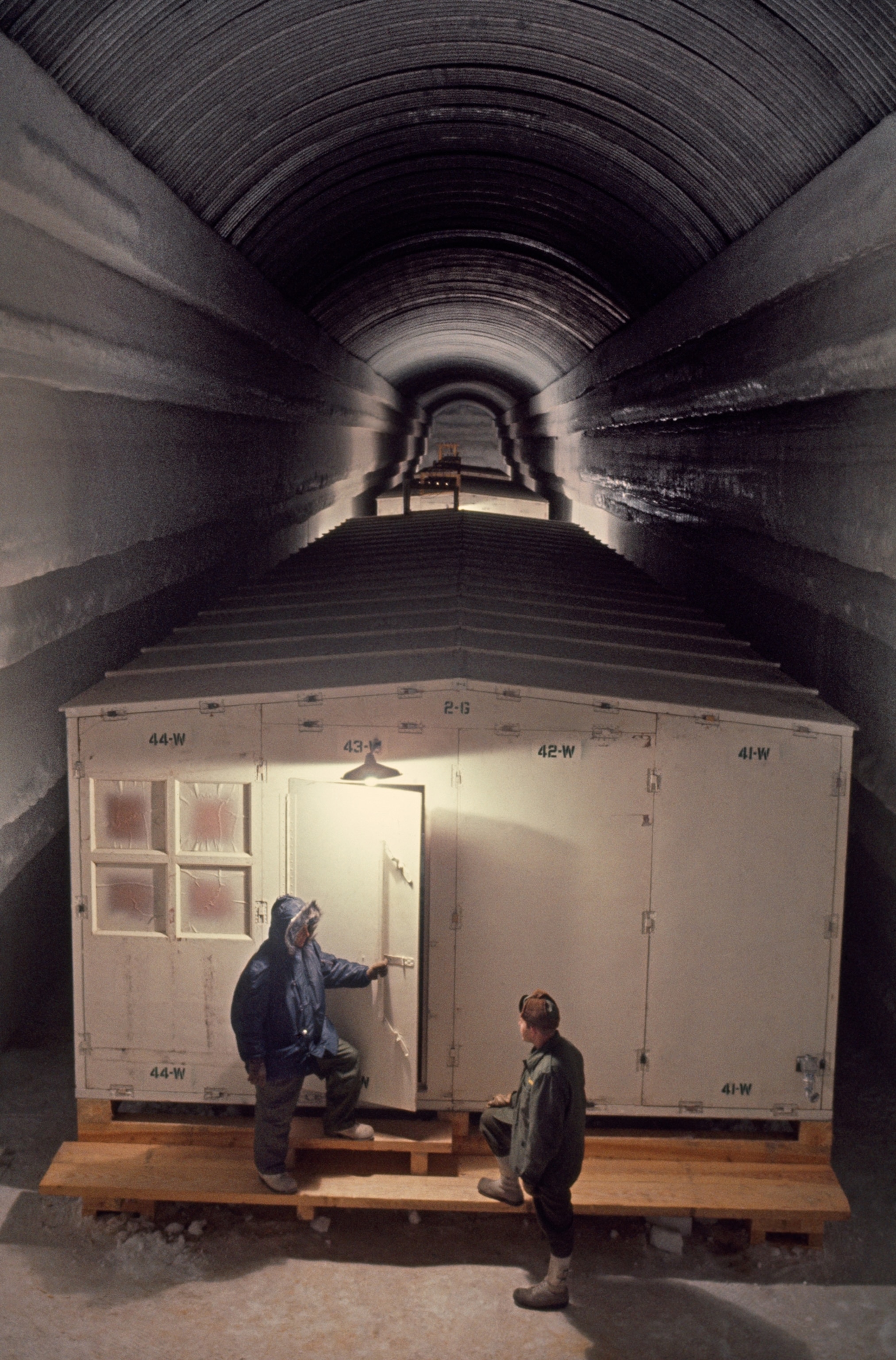 Two men stand outside barracks in an Arctic outpost's tunnel