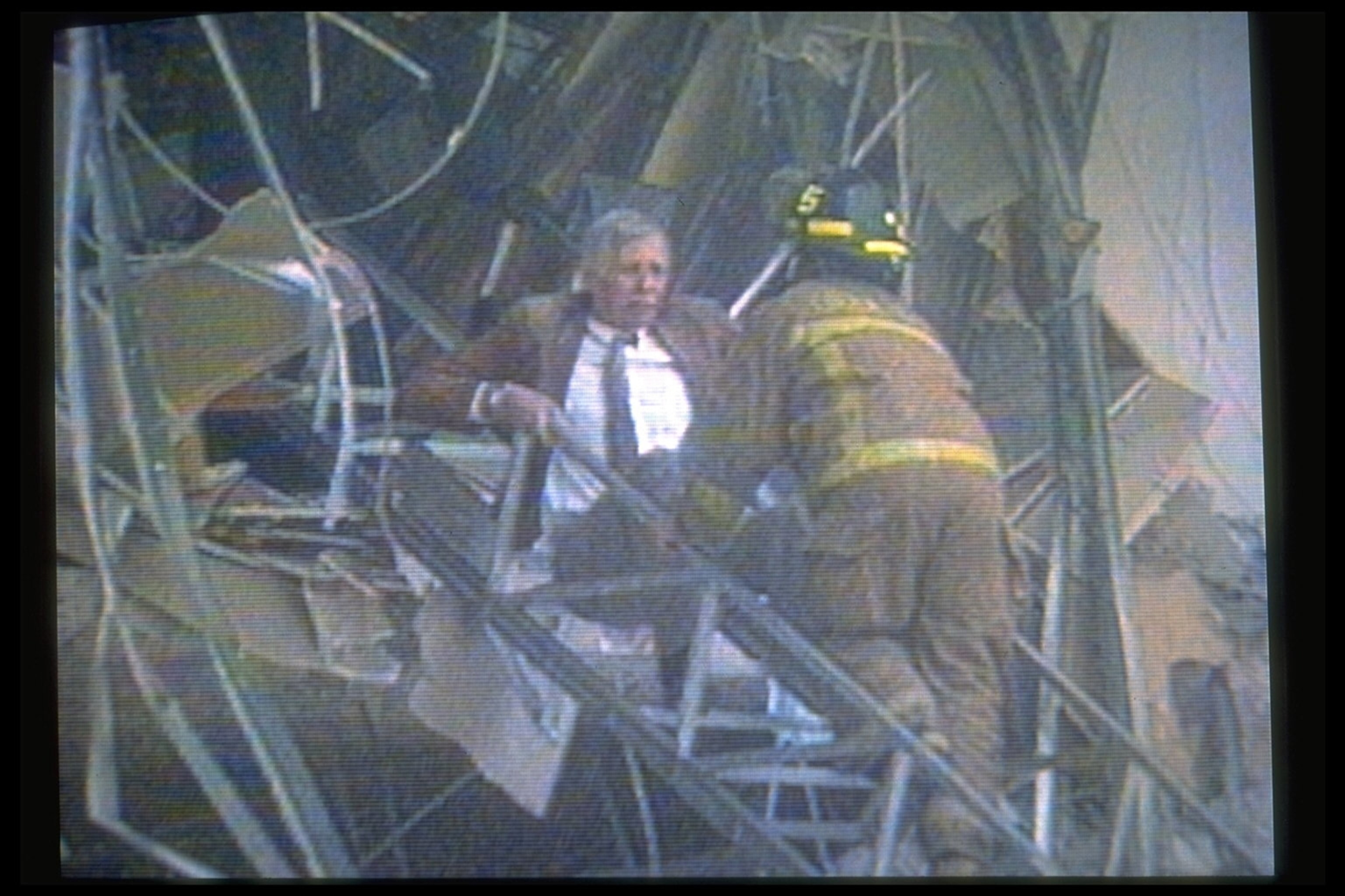 A firefighter assists a man down a ladder protruding from a destroyed building.