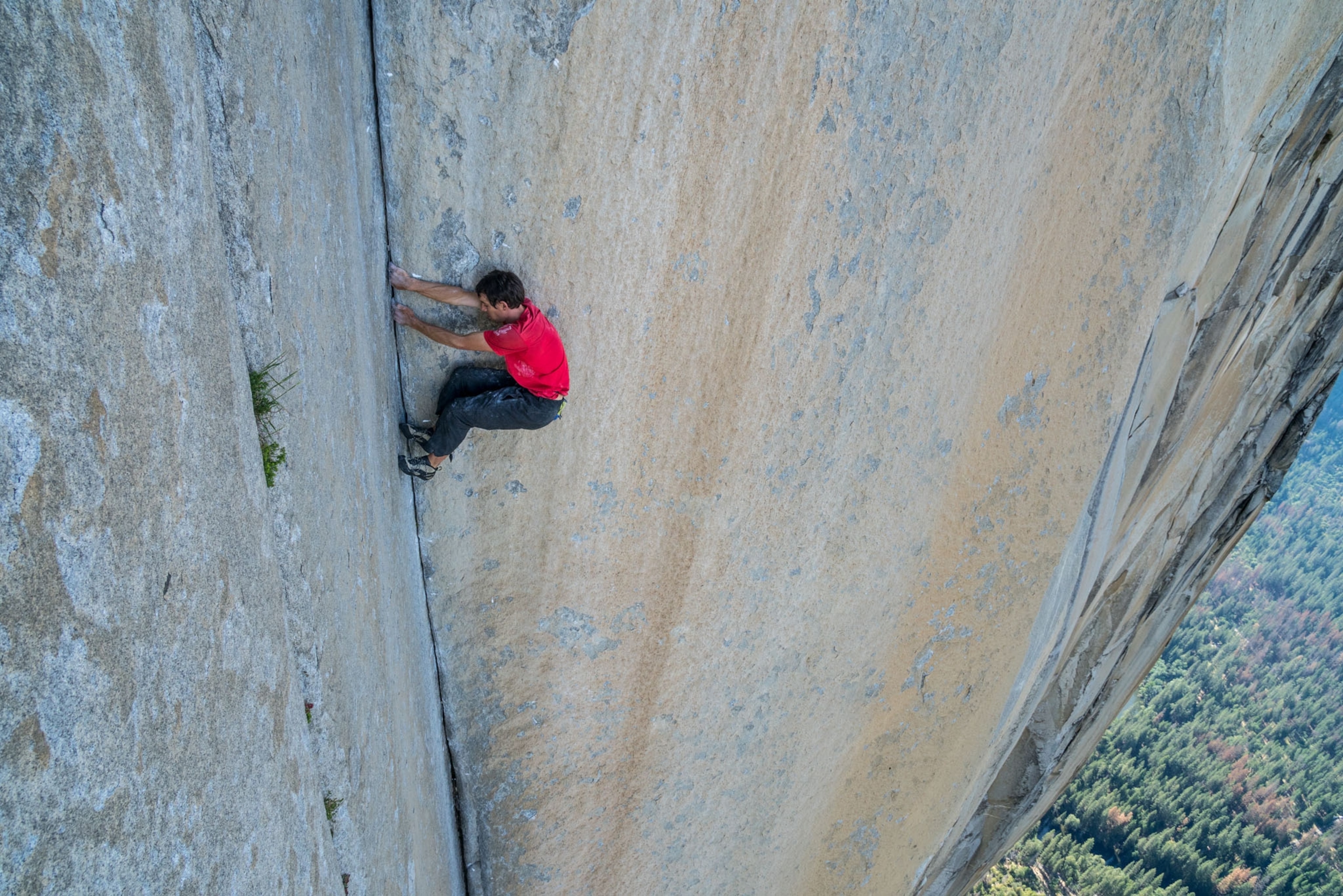a man climbing a narrow crack in a mountain
