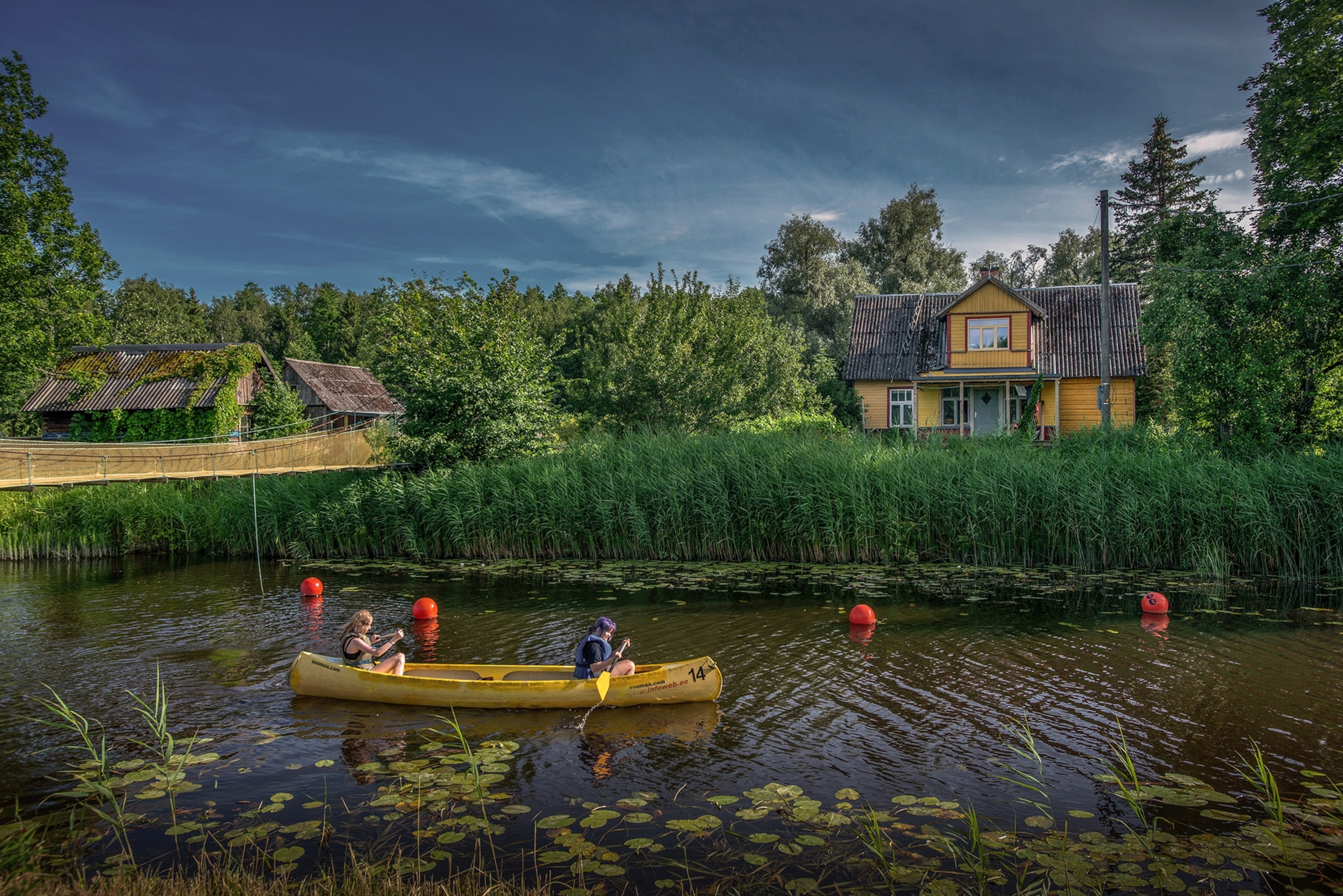 Women paddle on boat on river.
