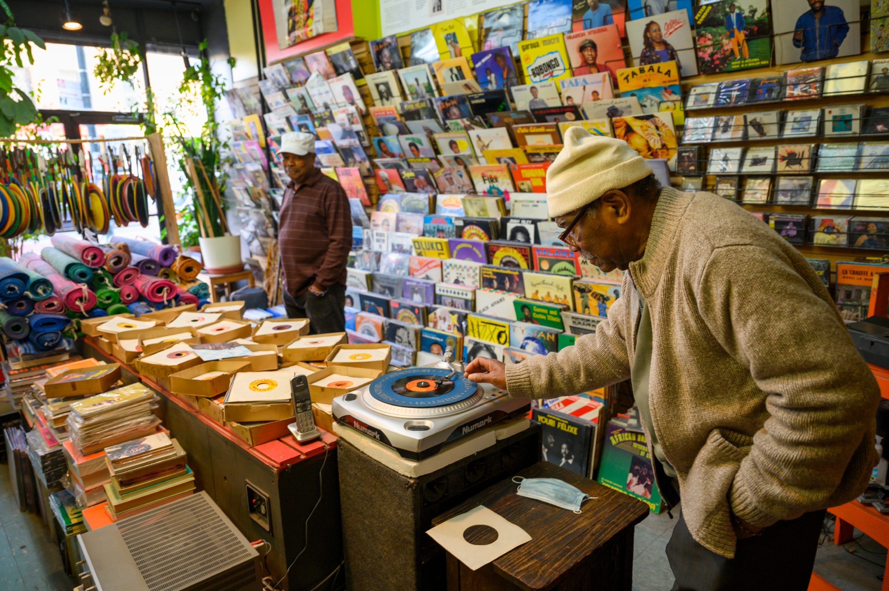 Two men listen to music in a shop surrounded by vinyl records