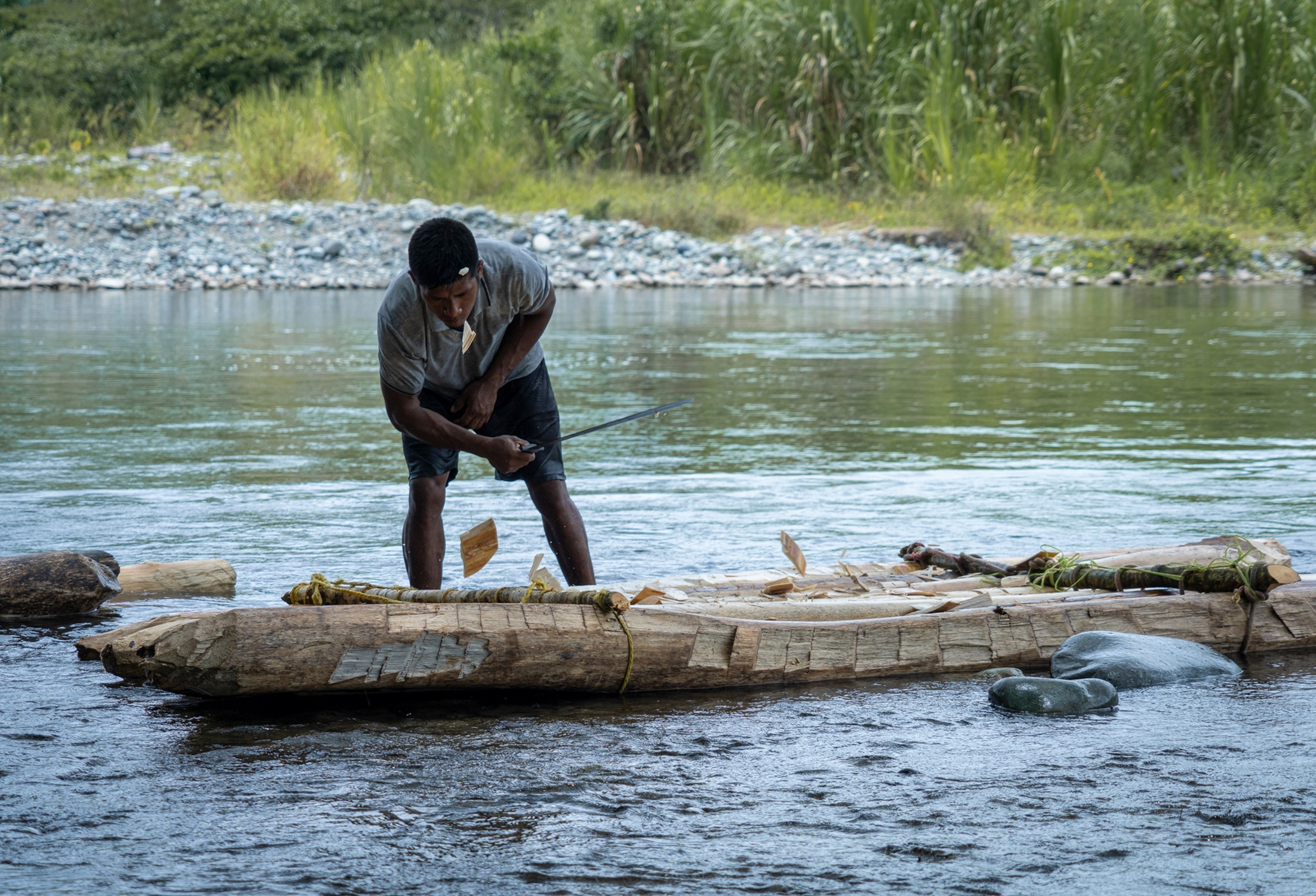 Man cuts wood, carving raft.