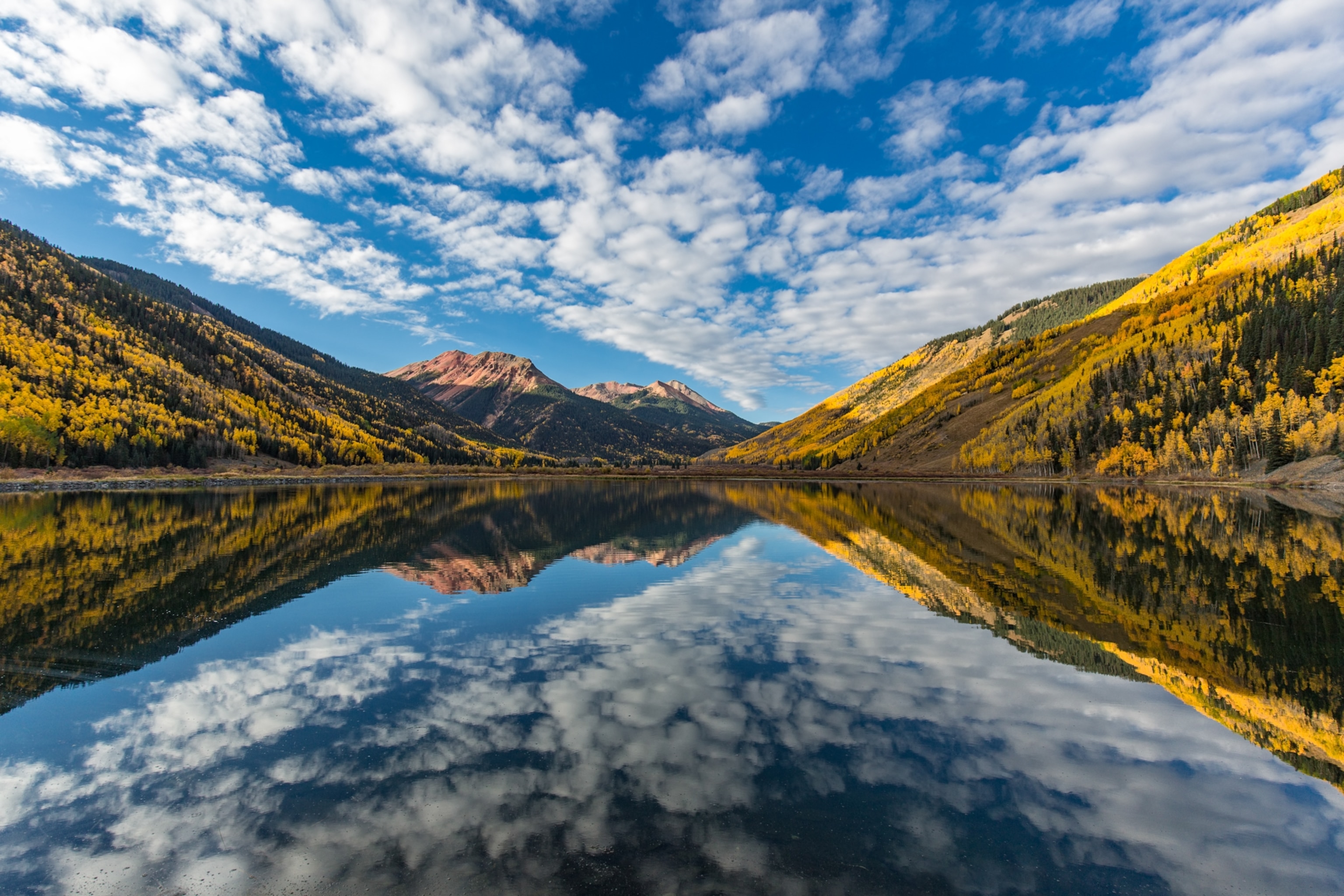 A reflection of a blue sky and clouds into a lake.