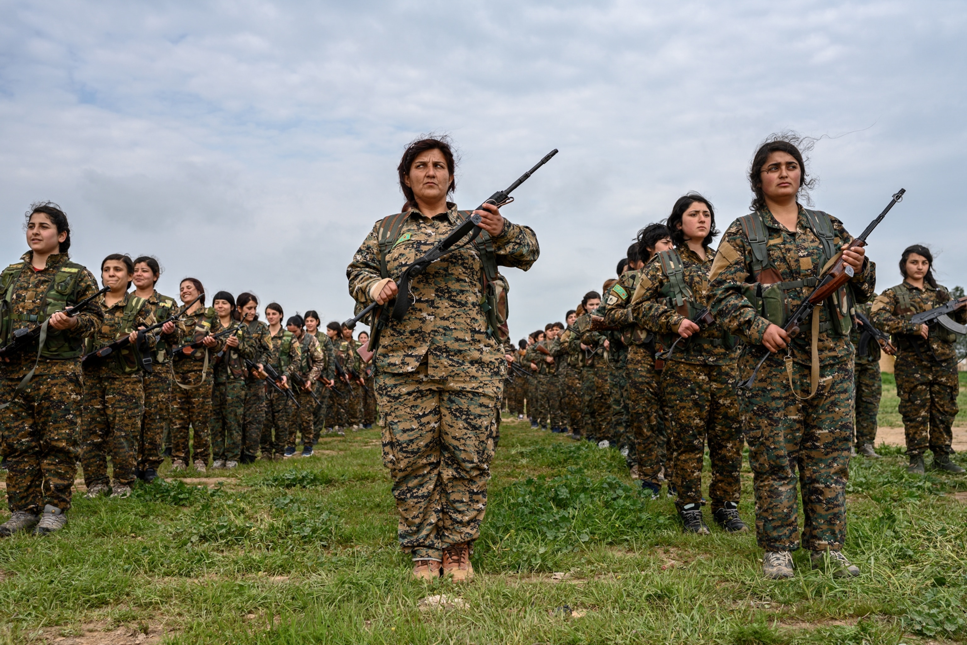 many woman in uniform in line, holding guns across their chest