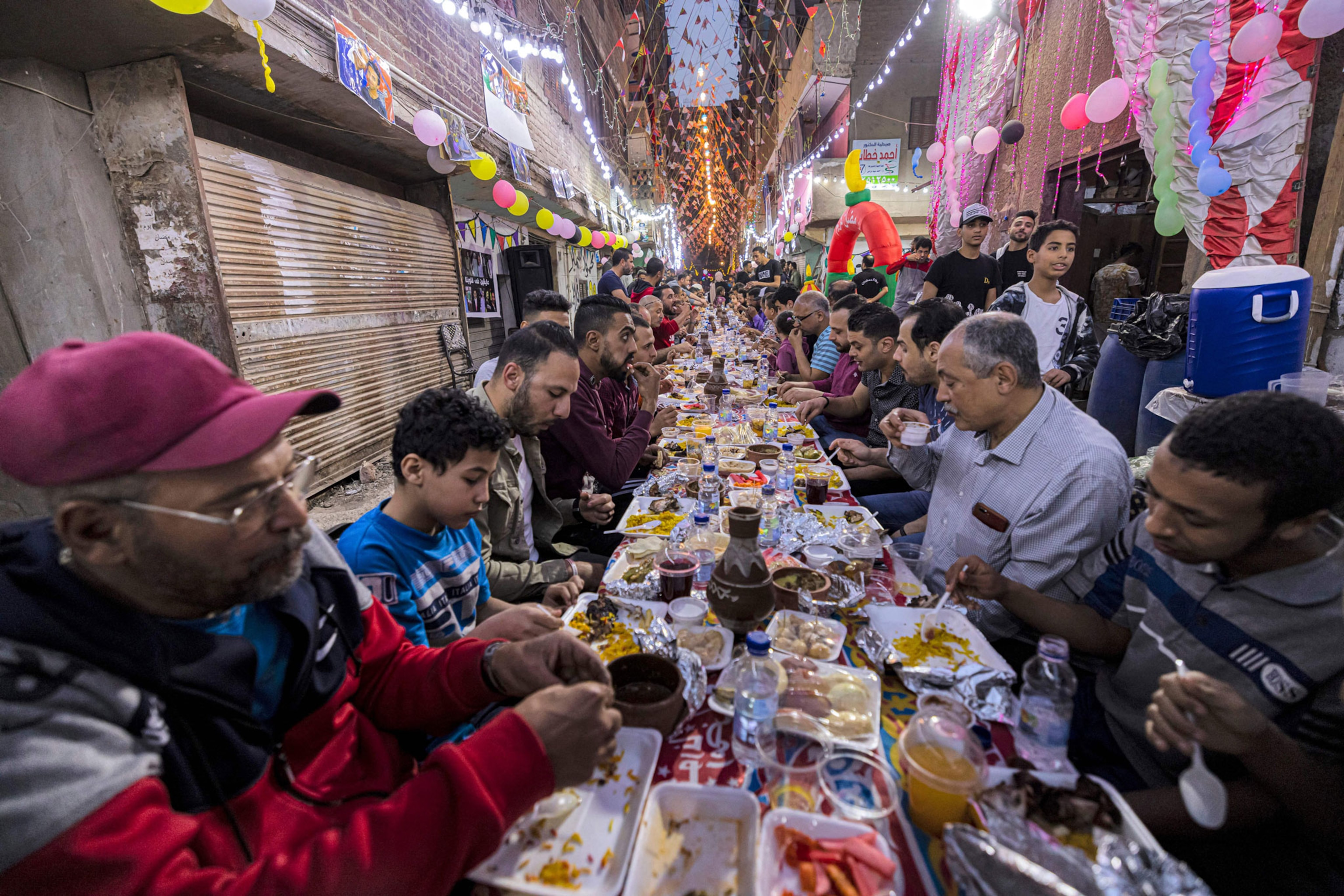 Muslims gather along a street-long table for break their Ramadan fast together in a mass
