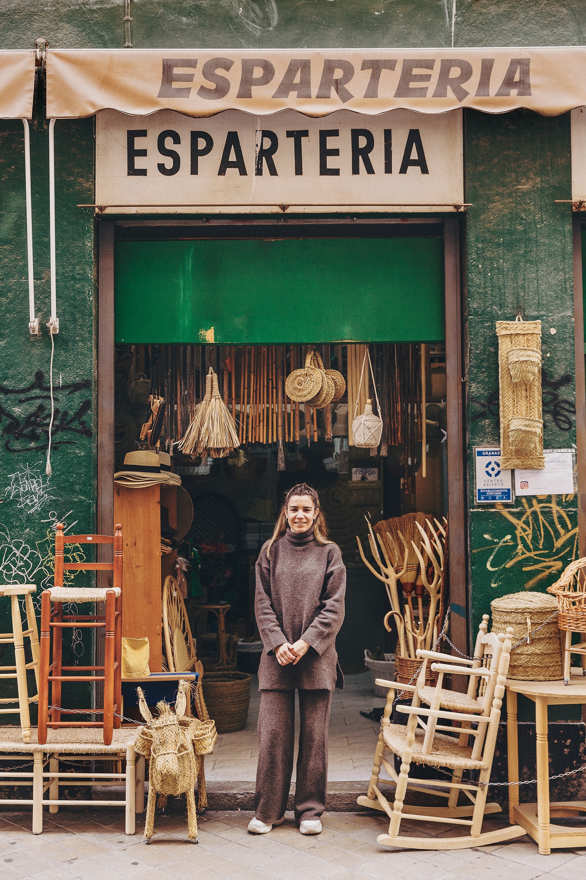 A woman stands outside the basket shop her family owns and runs in Granada's historic old town