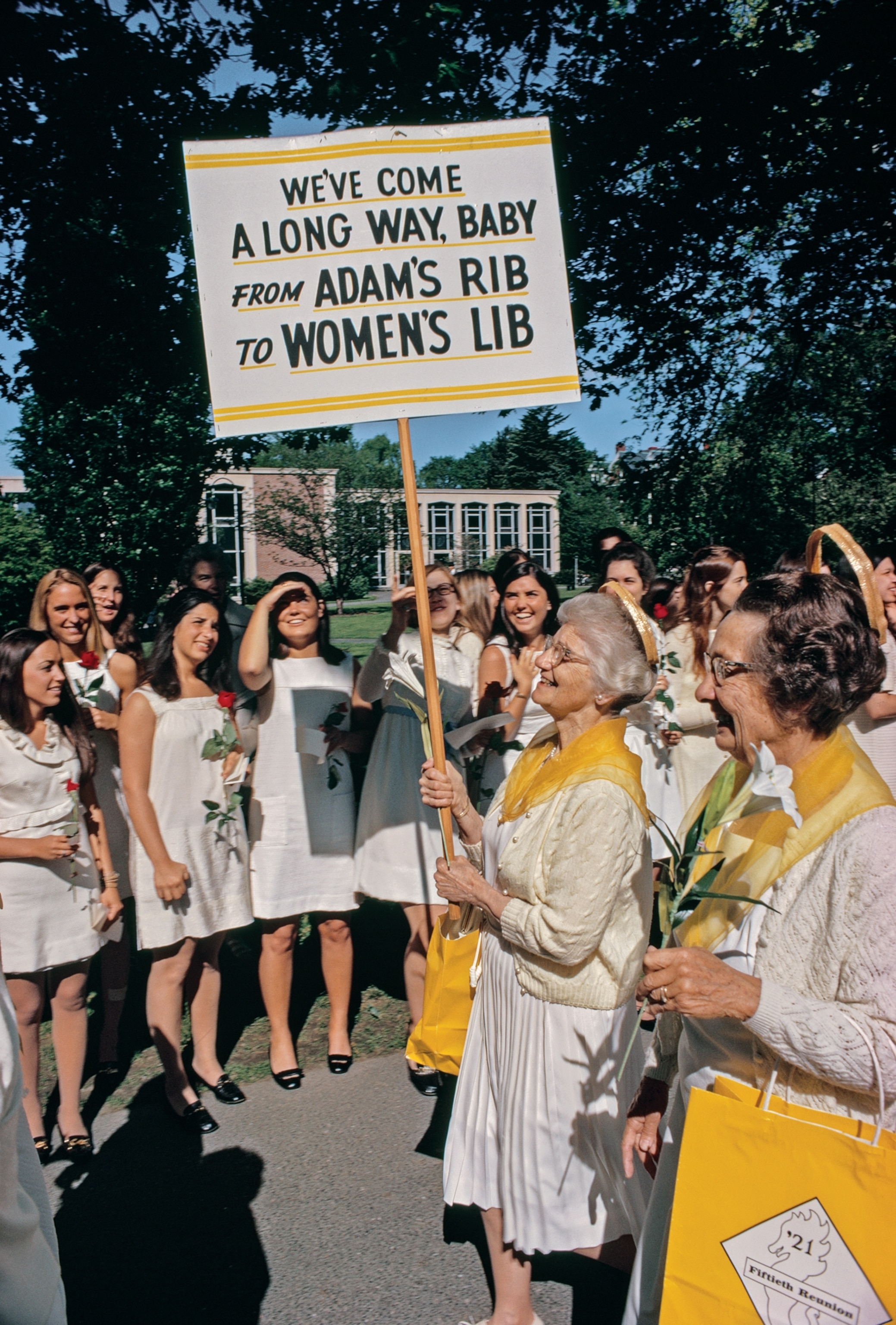 older alumnae members marching before before new graduates.