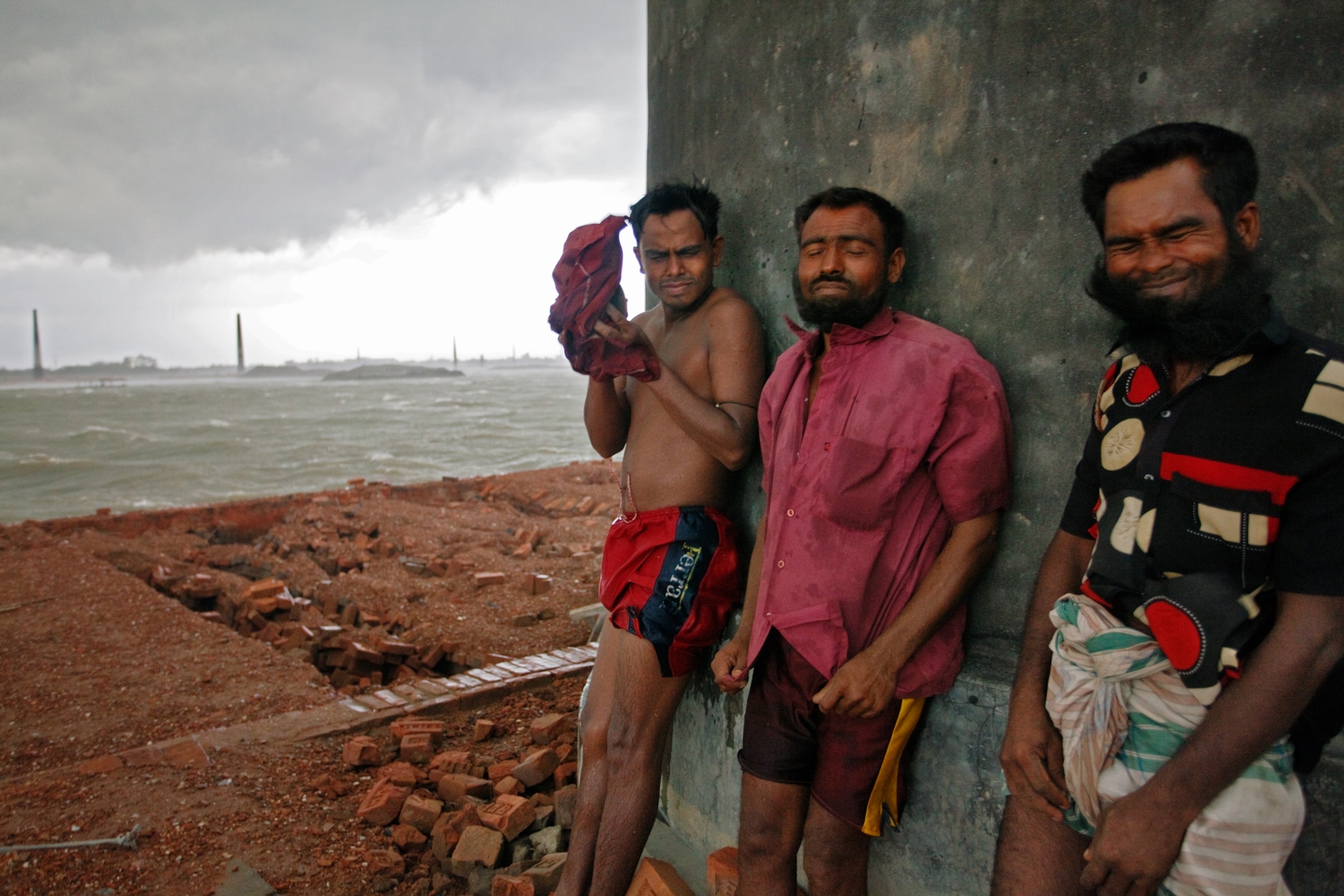 brick workers absorbing the sting of a driving rain on the Turag River