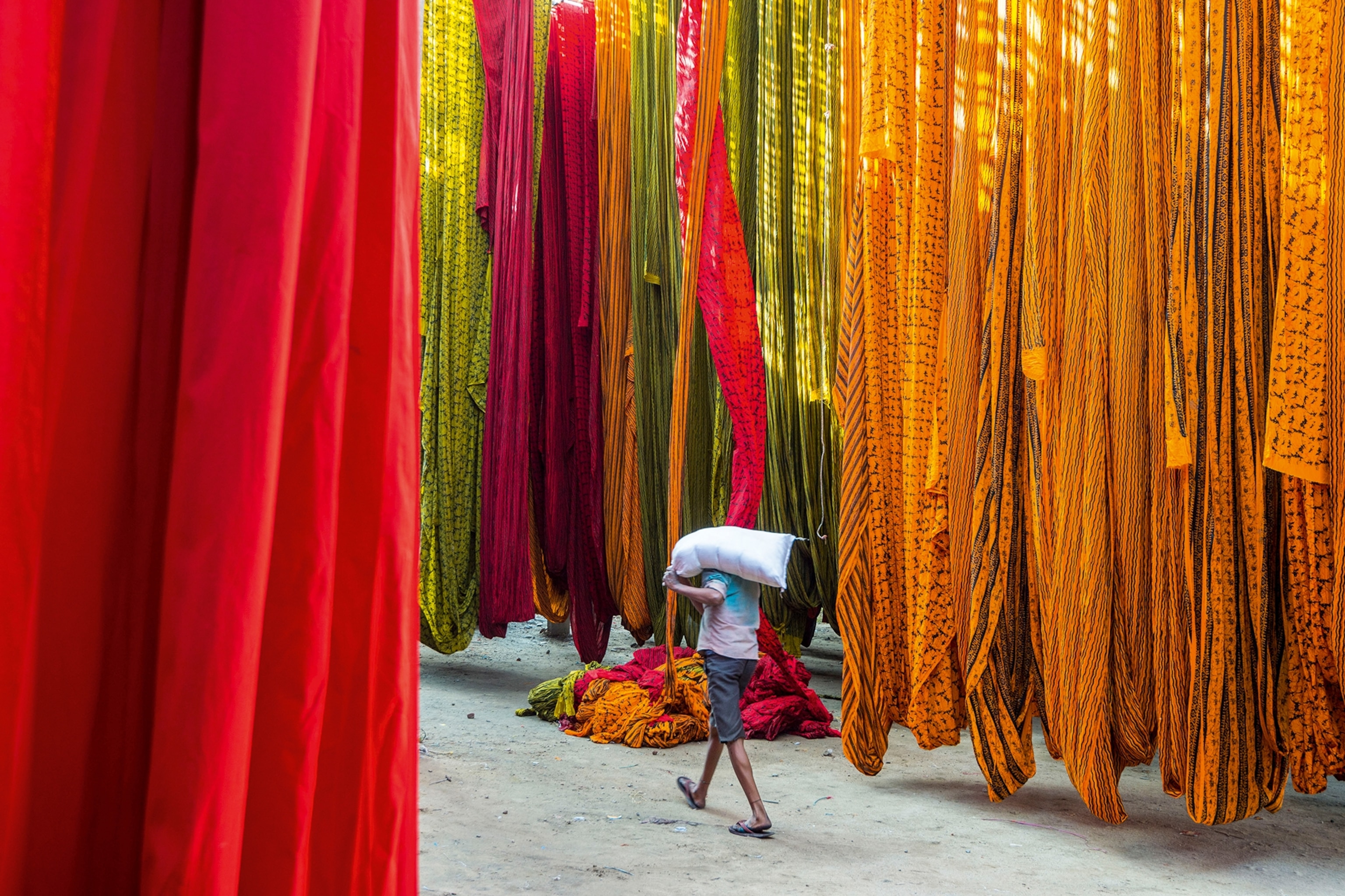Coloured fabric hanging with a man walking on a path in between