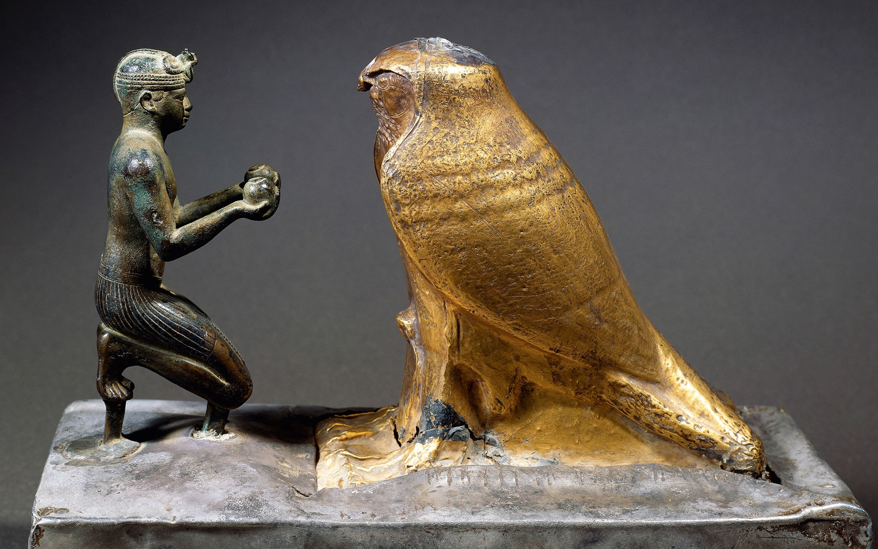 A kneeling person makes an offering to a falcon god in this bronze- and gold-leaf statuette