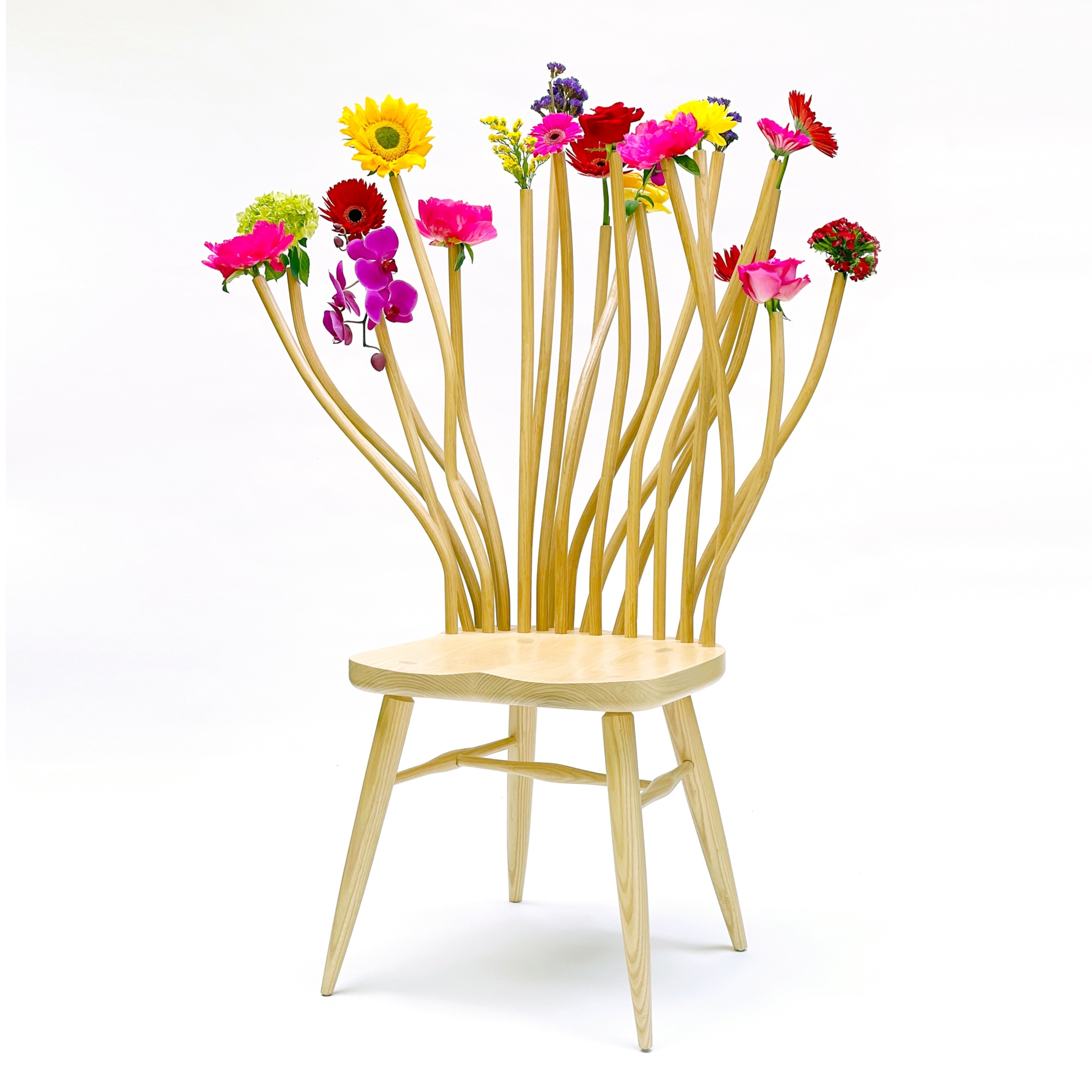 Wooden chair with stemmed flowers sticking out of the seat back