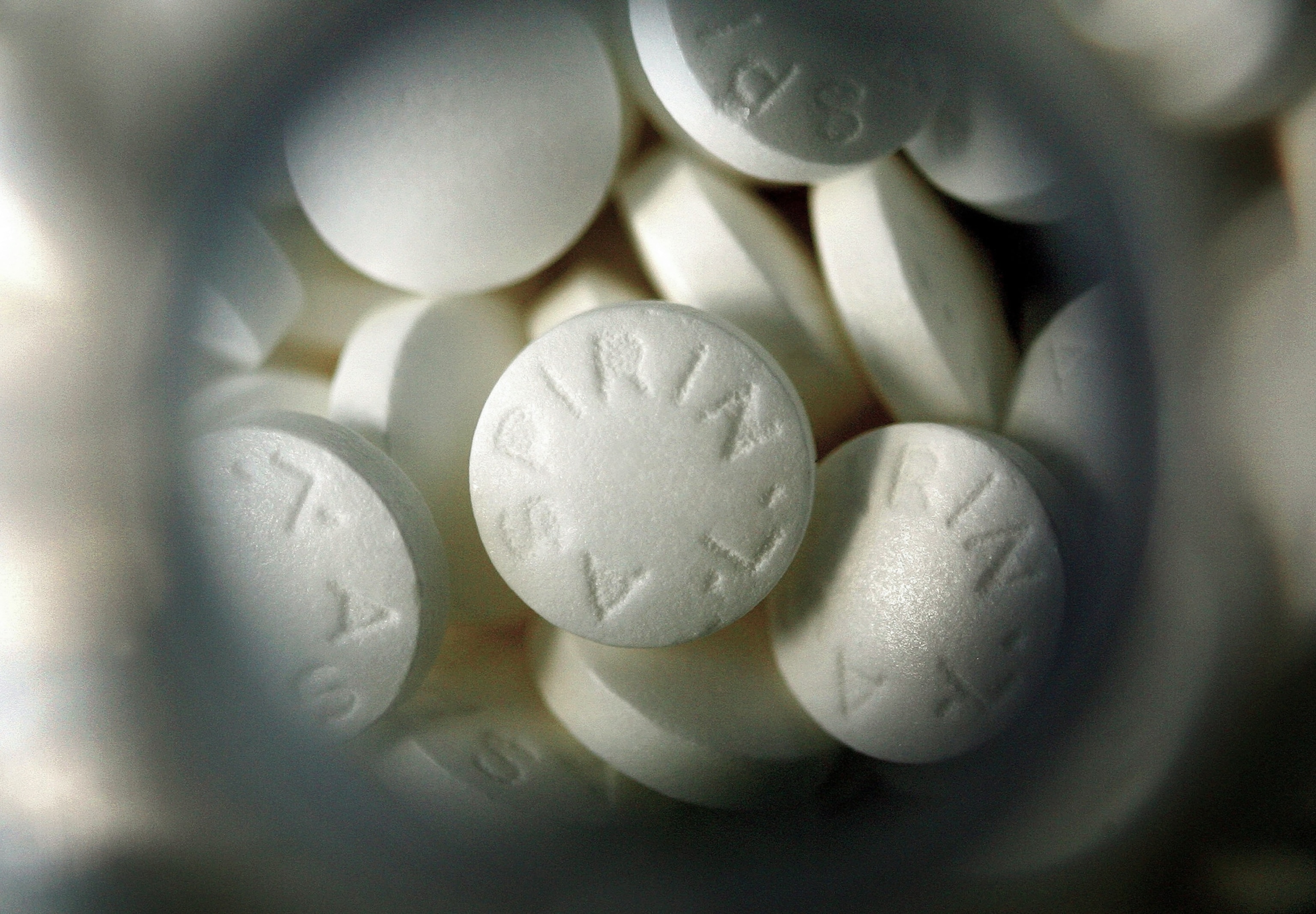 Generic aspirin inside a glass bottle, viewed top-down through the opening.