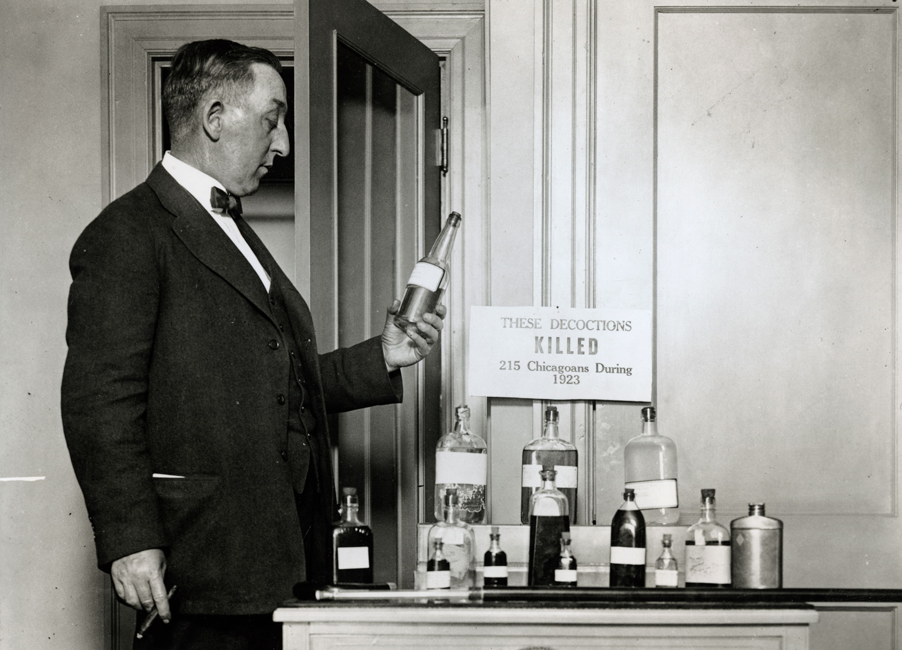A man holds a bottle from a display of alcohol .