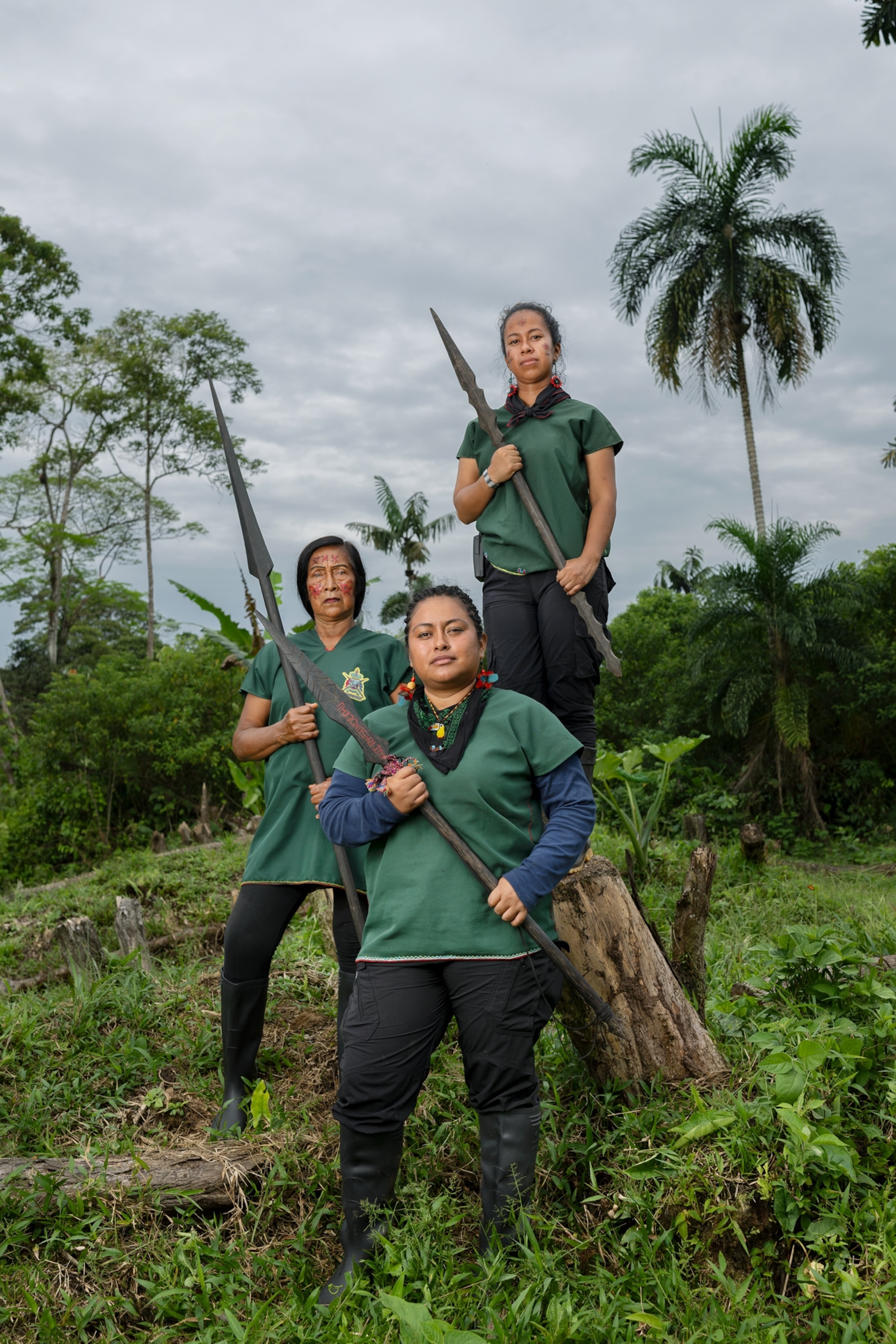 Three women pose in the forest holding spears