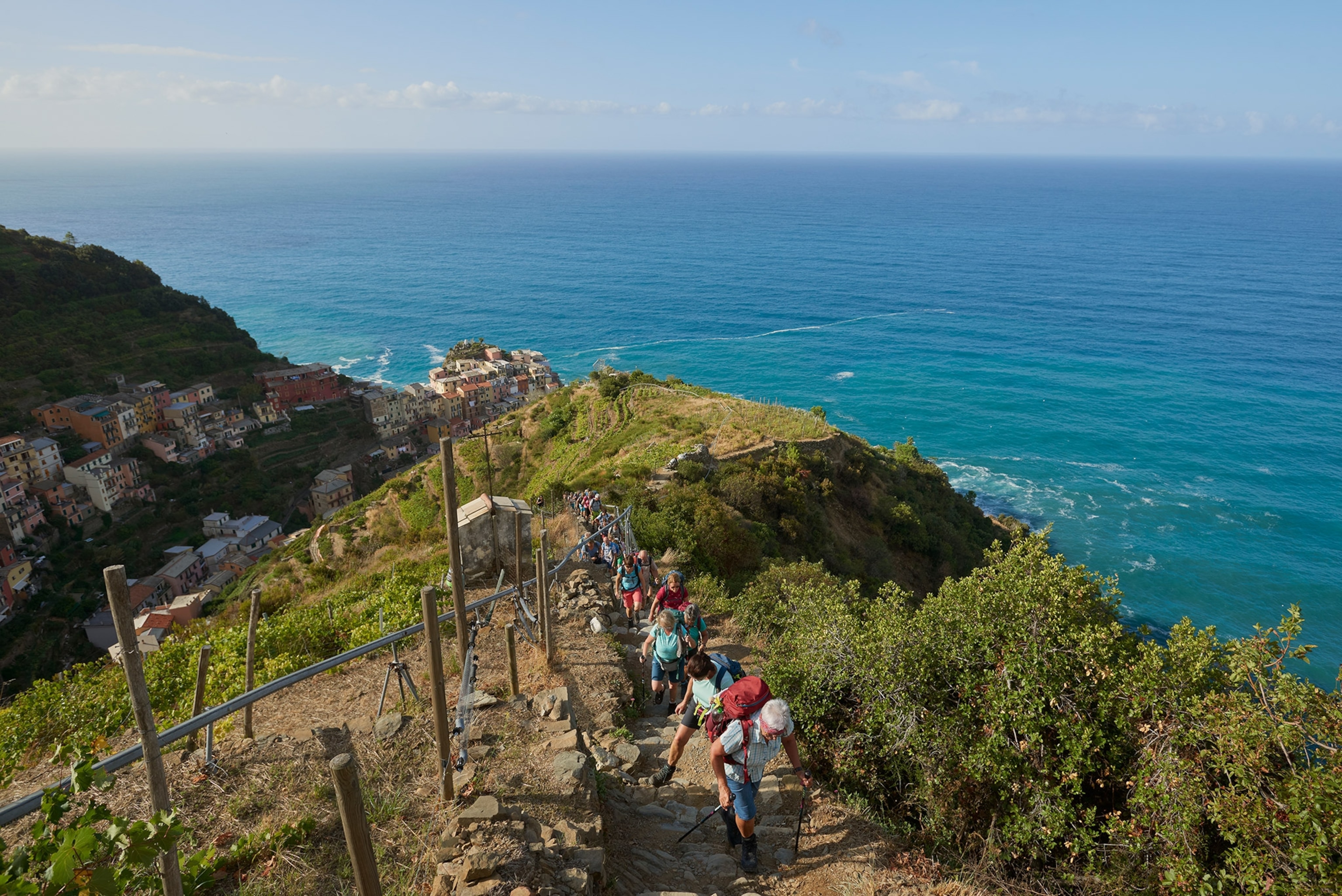 A group of tourists walk up one of the trails above Manarola