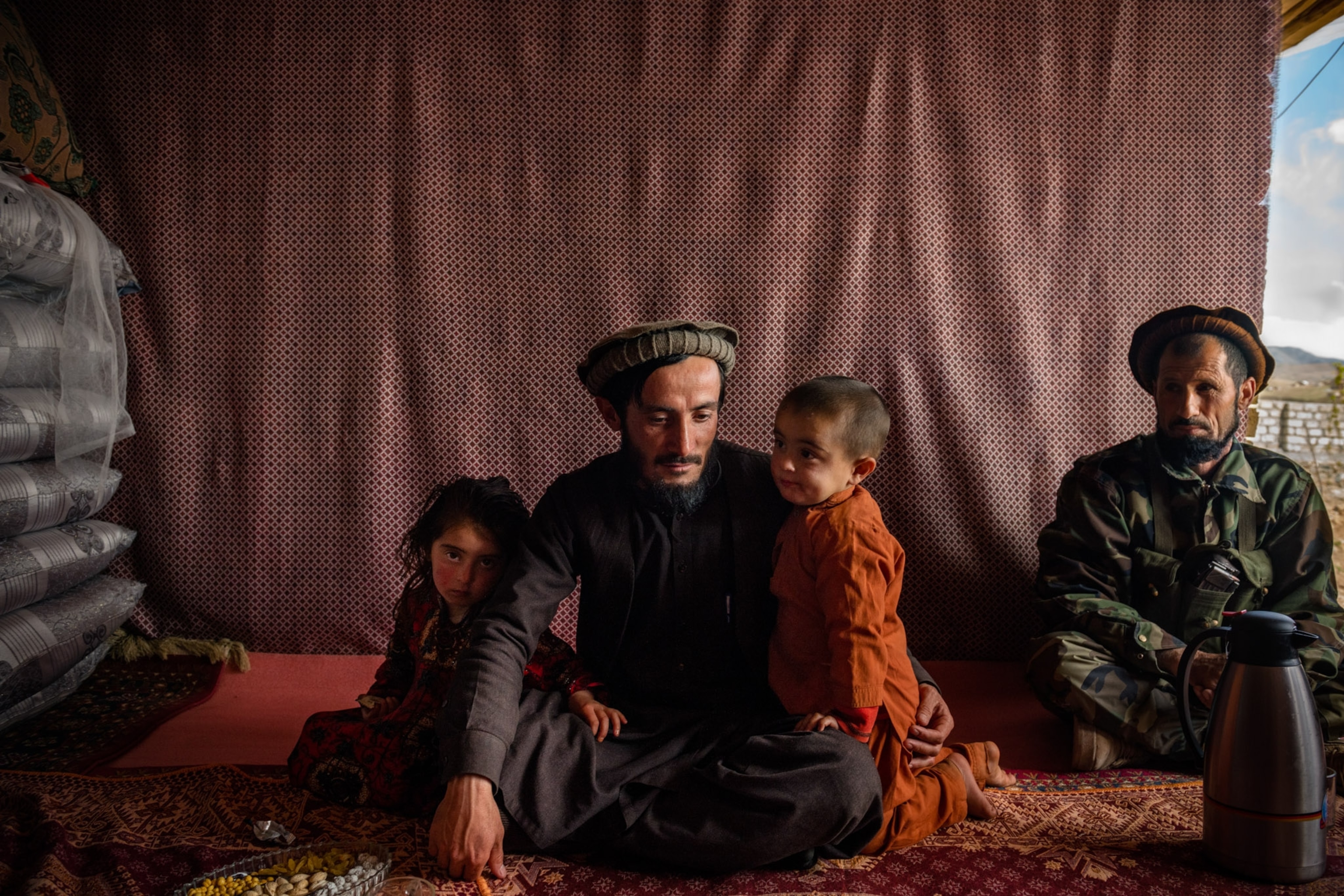 Picture of a man sitting with two children on a patterned floor