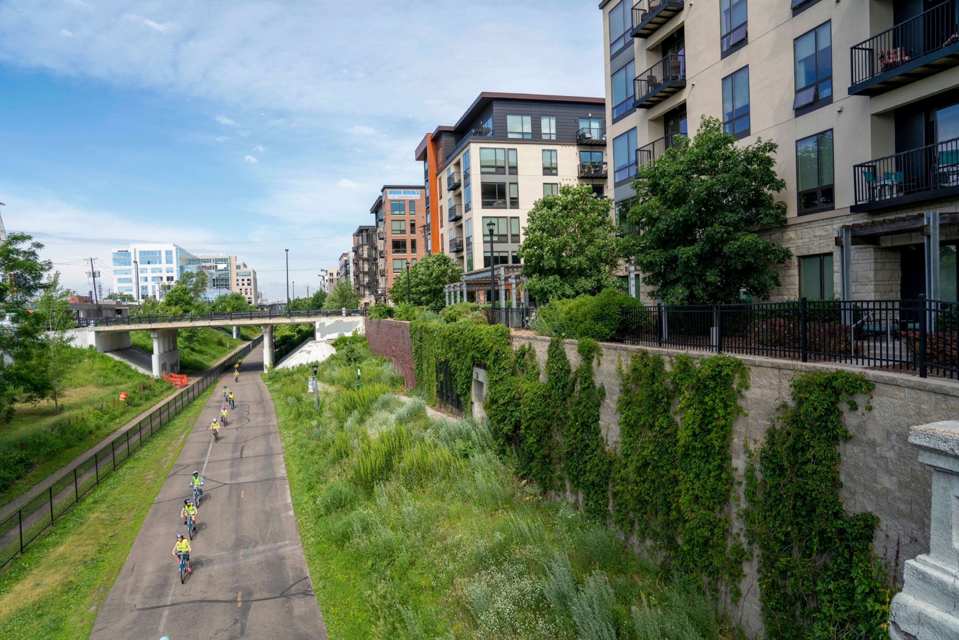 Young people biking on a path next to apartment buildings