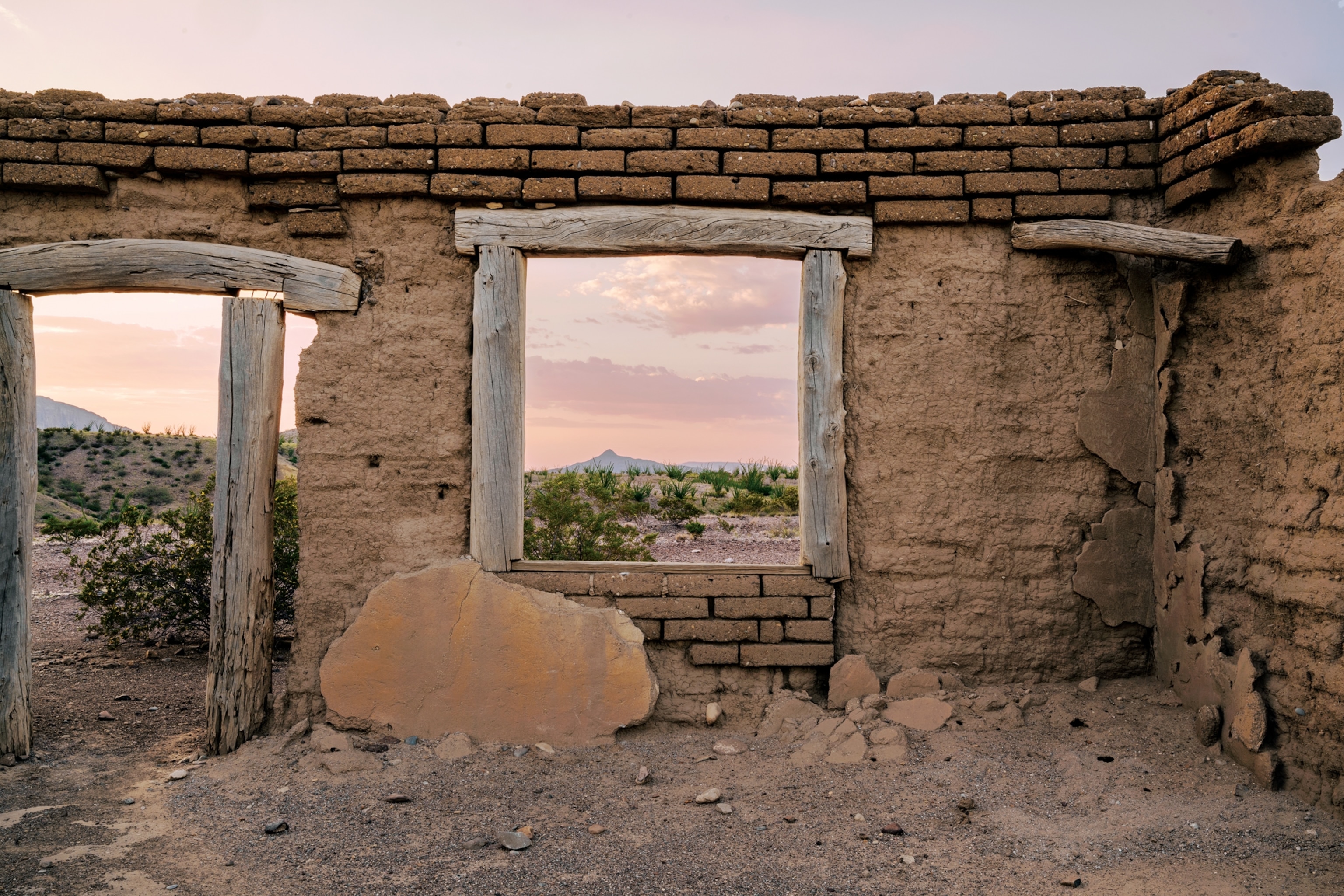 Picture of doorway and window in the wall of roofless stone house.