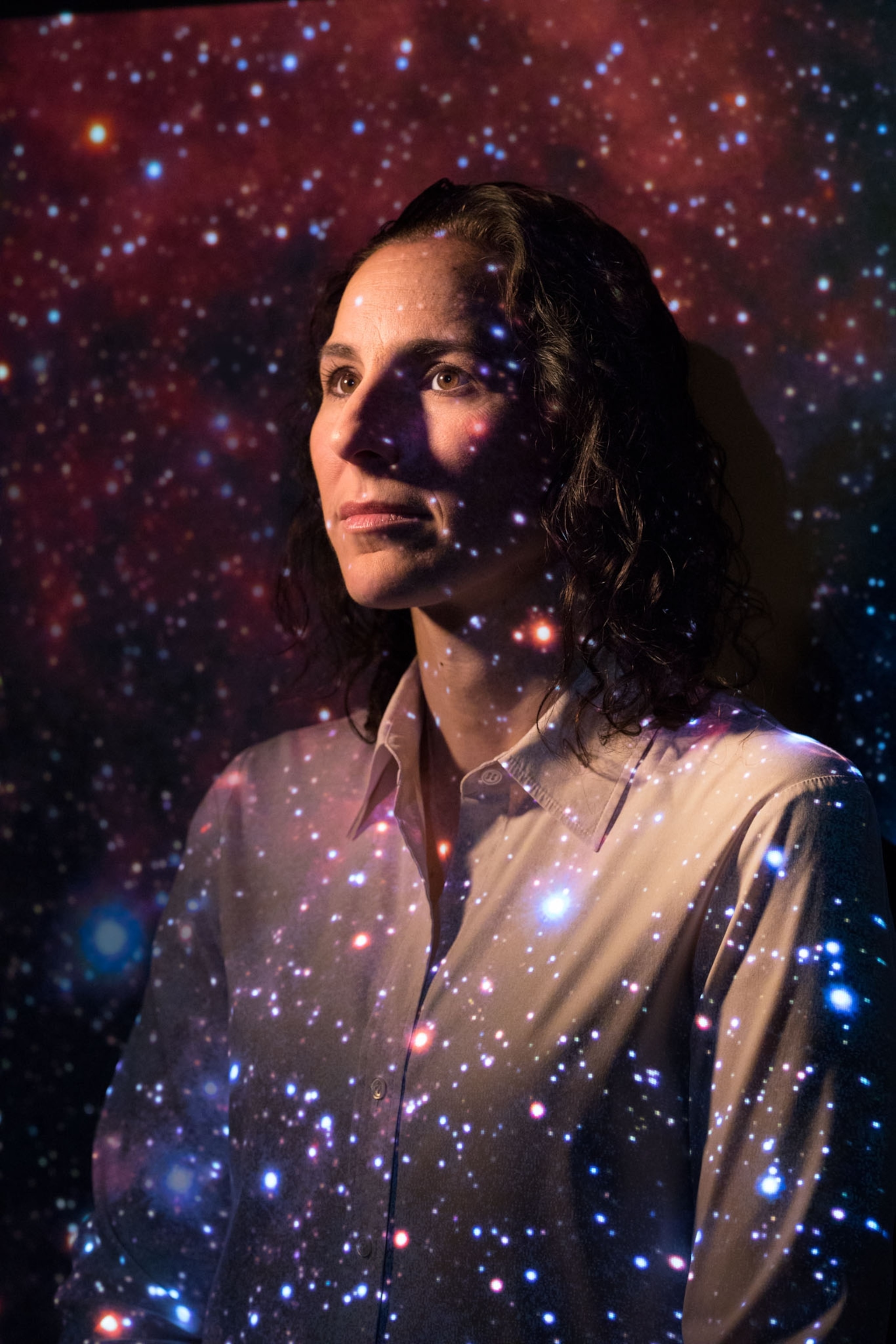 Juna Kollmeier with stars from a galaxy projected onto her face