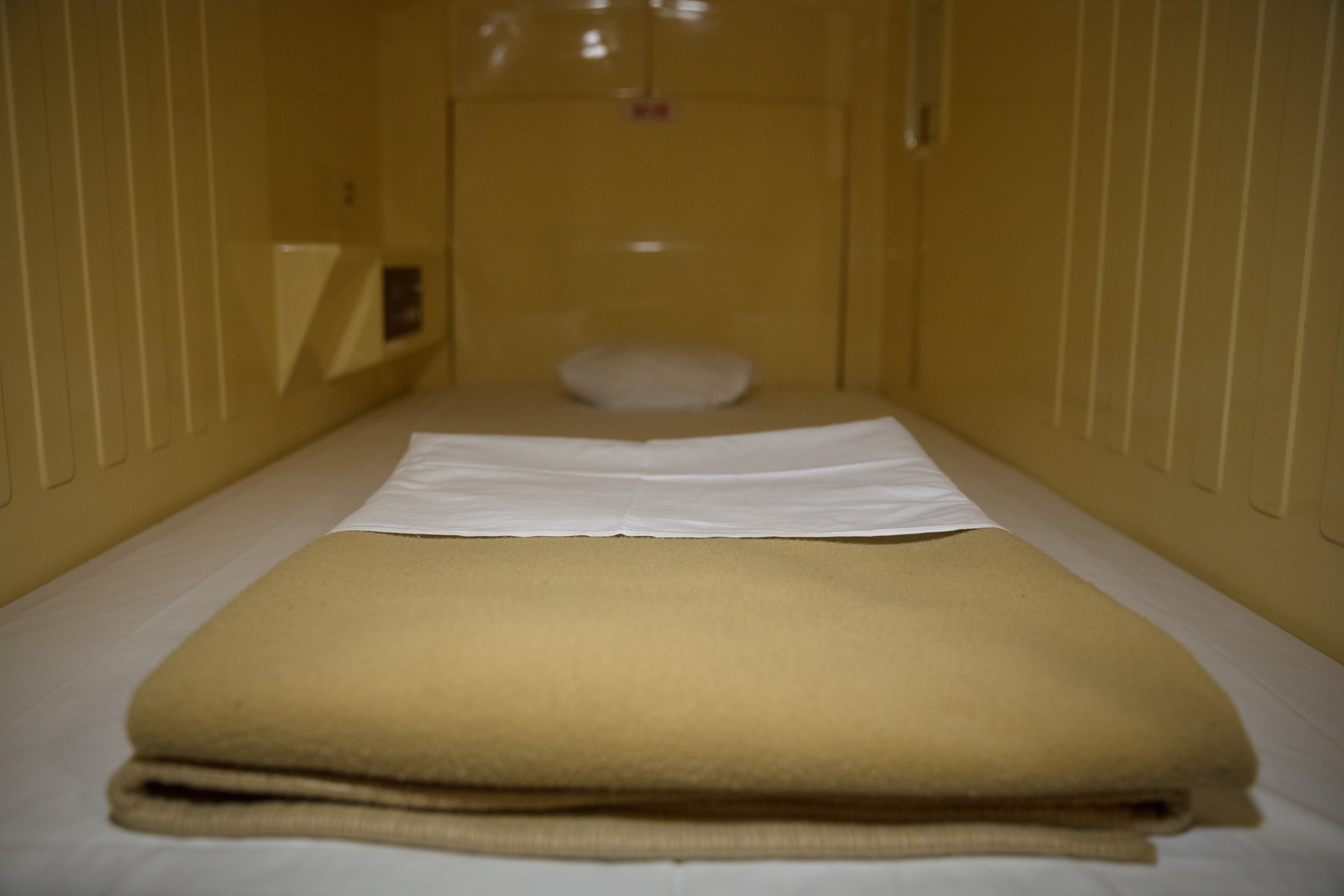 a dull yellow blanket folder on a bed in tight quarters