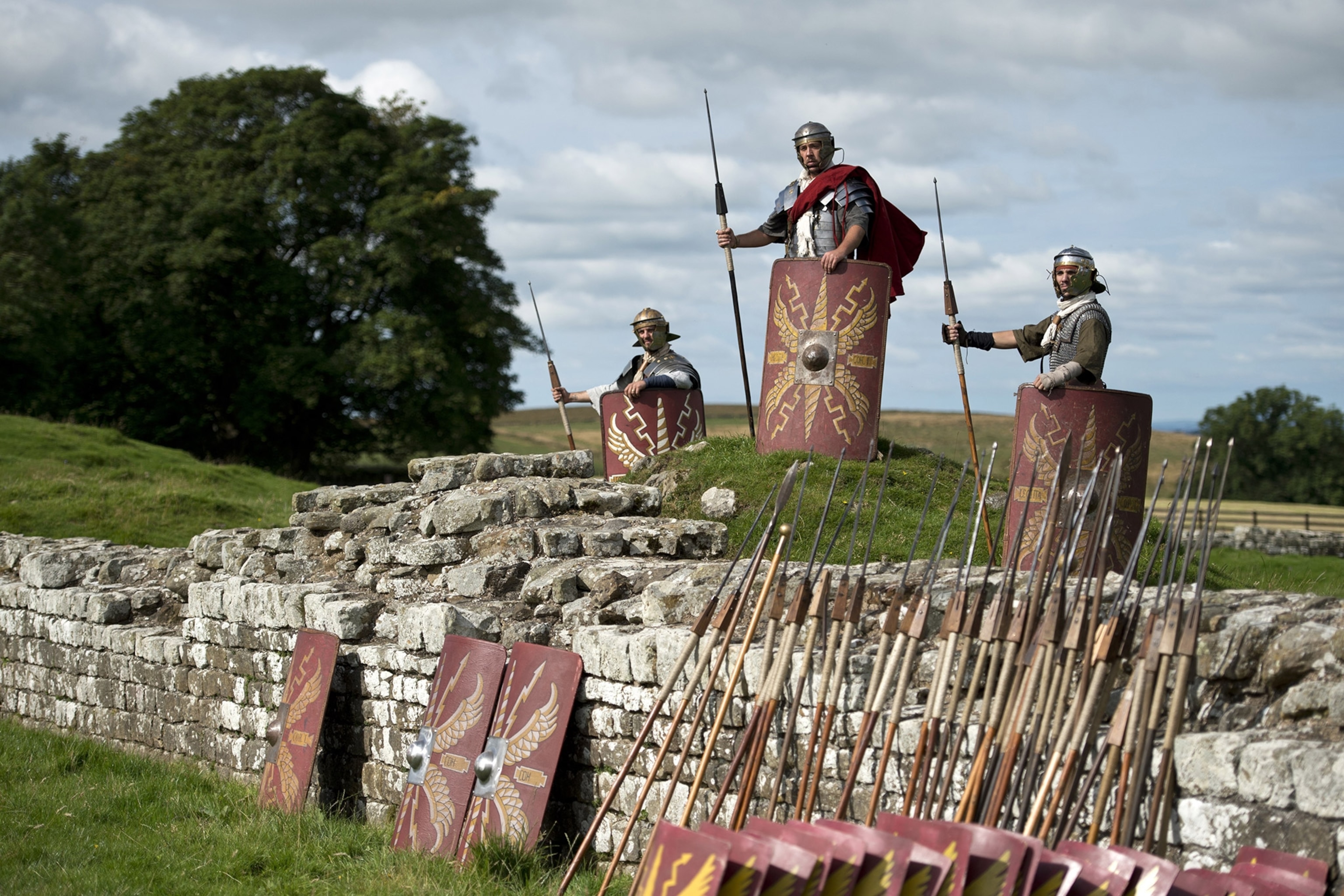 Reenactors portraying soldiers from the Imperial Roman Army pose for a photograph along the stones of Hadrian's Wall