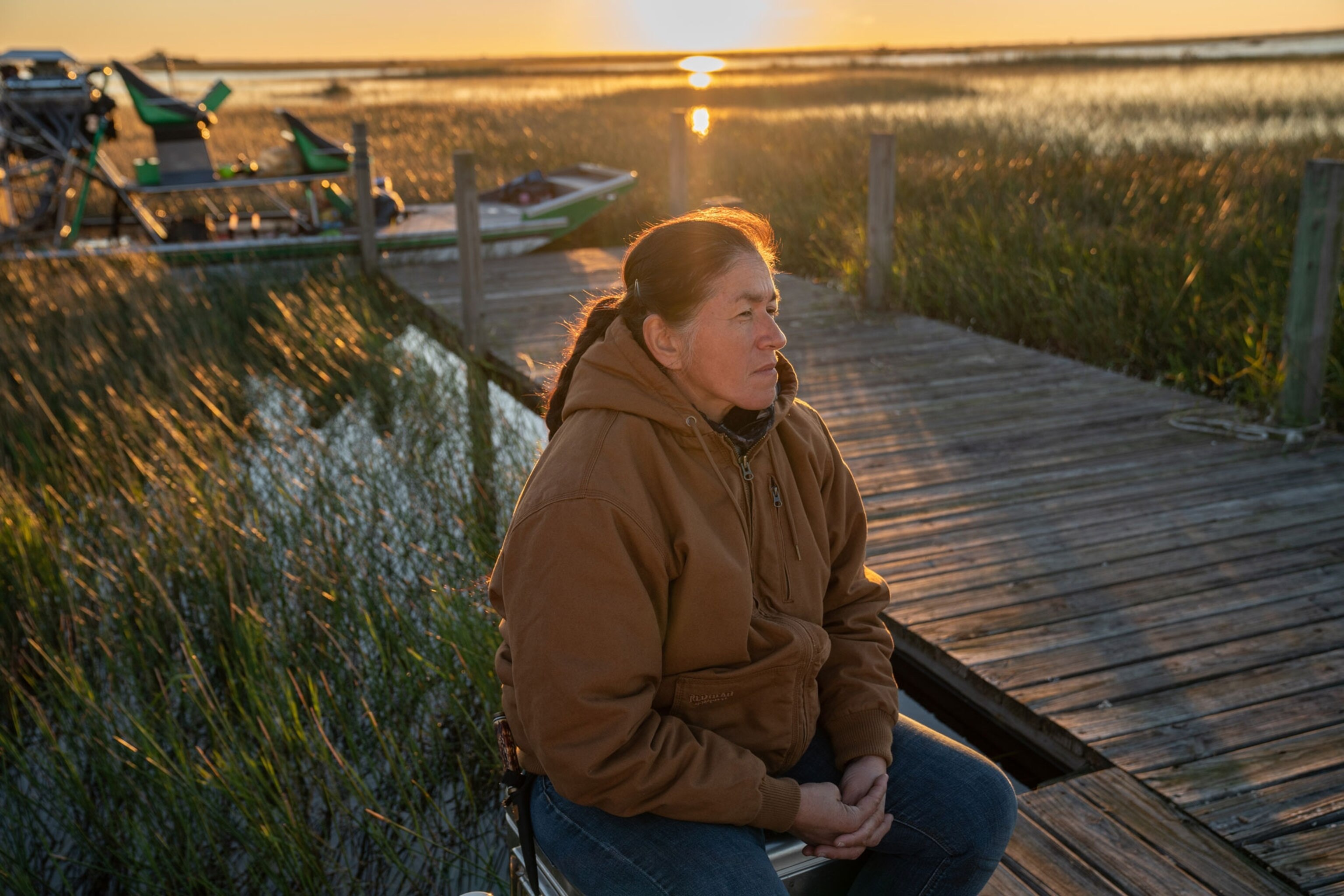 a woman sits on a dock in the everglades
