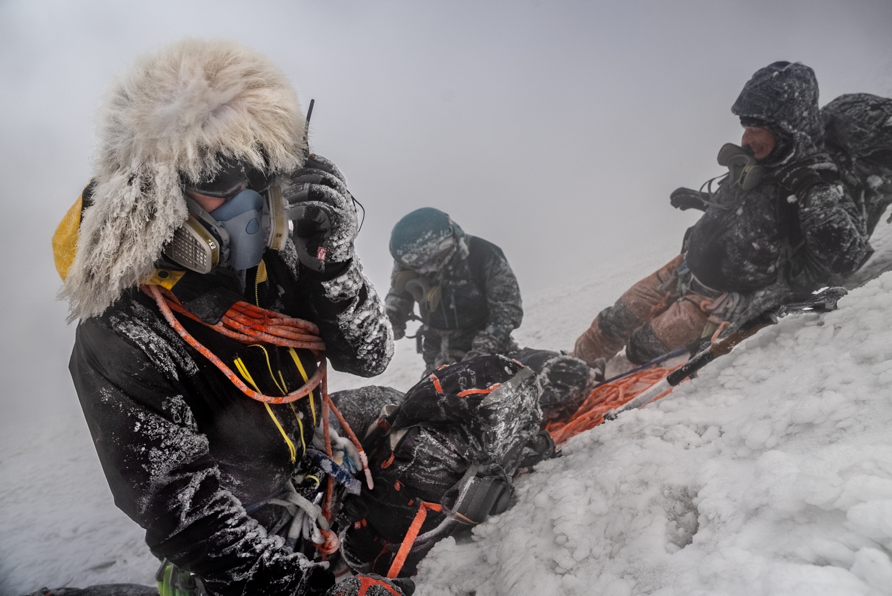 Three persons in blizzard, one talking on the phone.