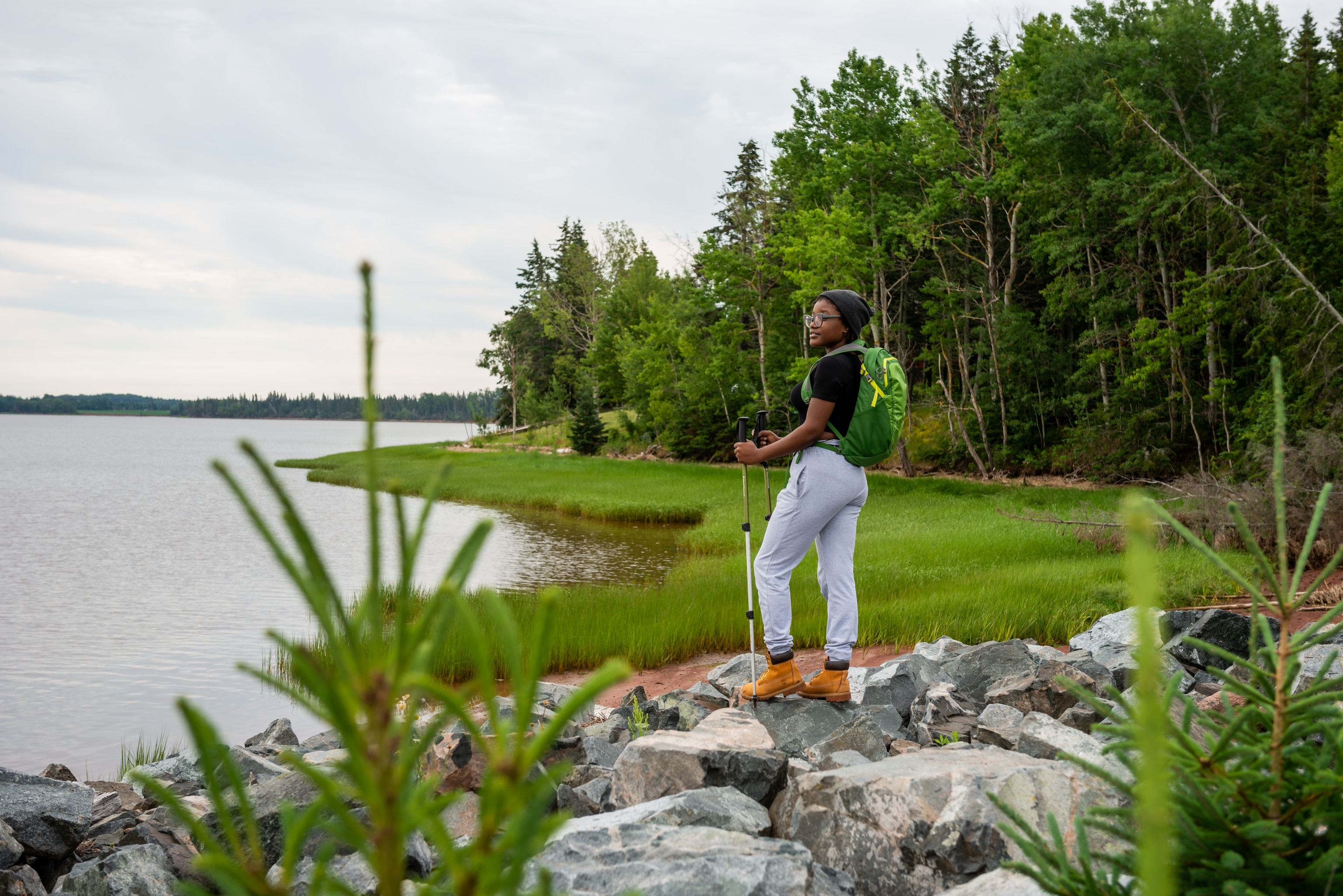 A hiker looks out over the water from the shore