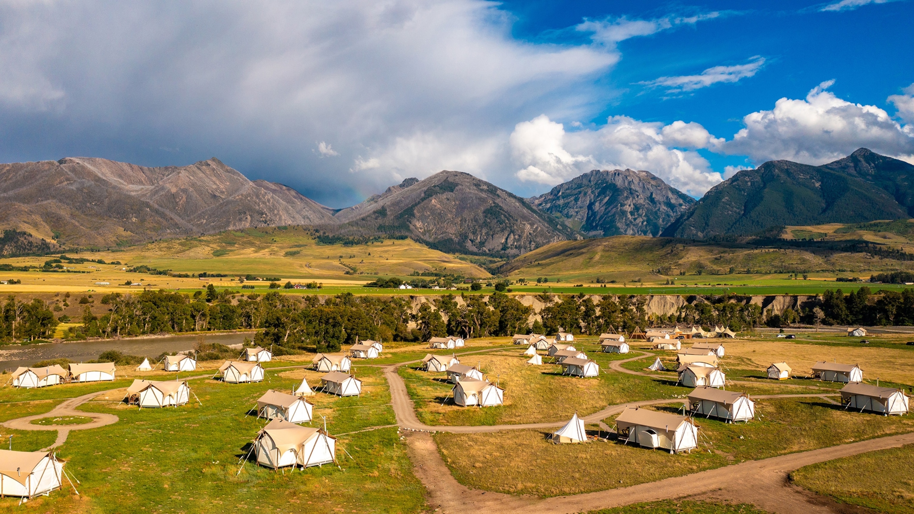 Glamping tents spread across Montana’s Paradise Valley with the Absaroka and Gallatin mountains in the background.