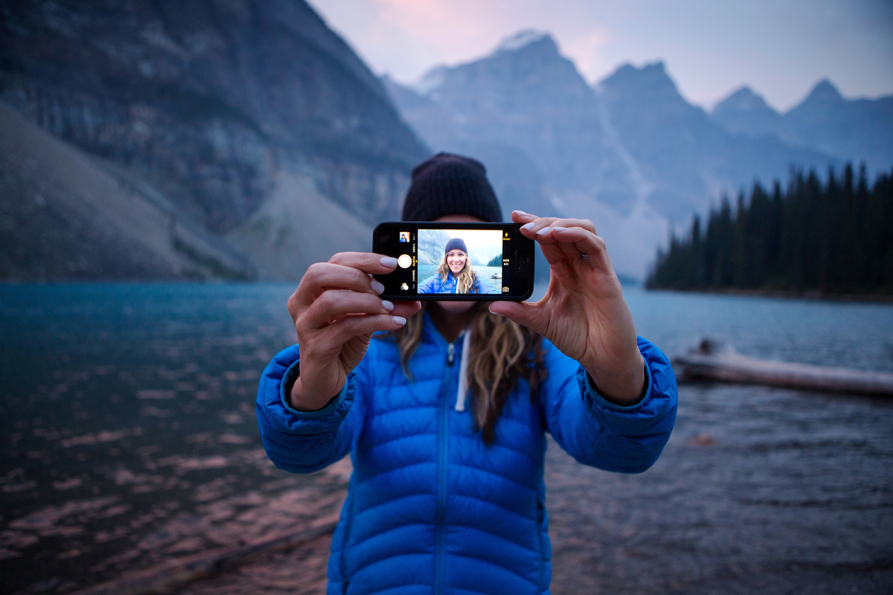 a woman taking an iPhone selfie at Moraine Lake in Banff National Park