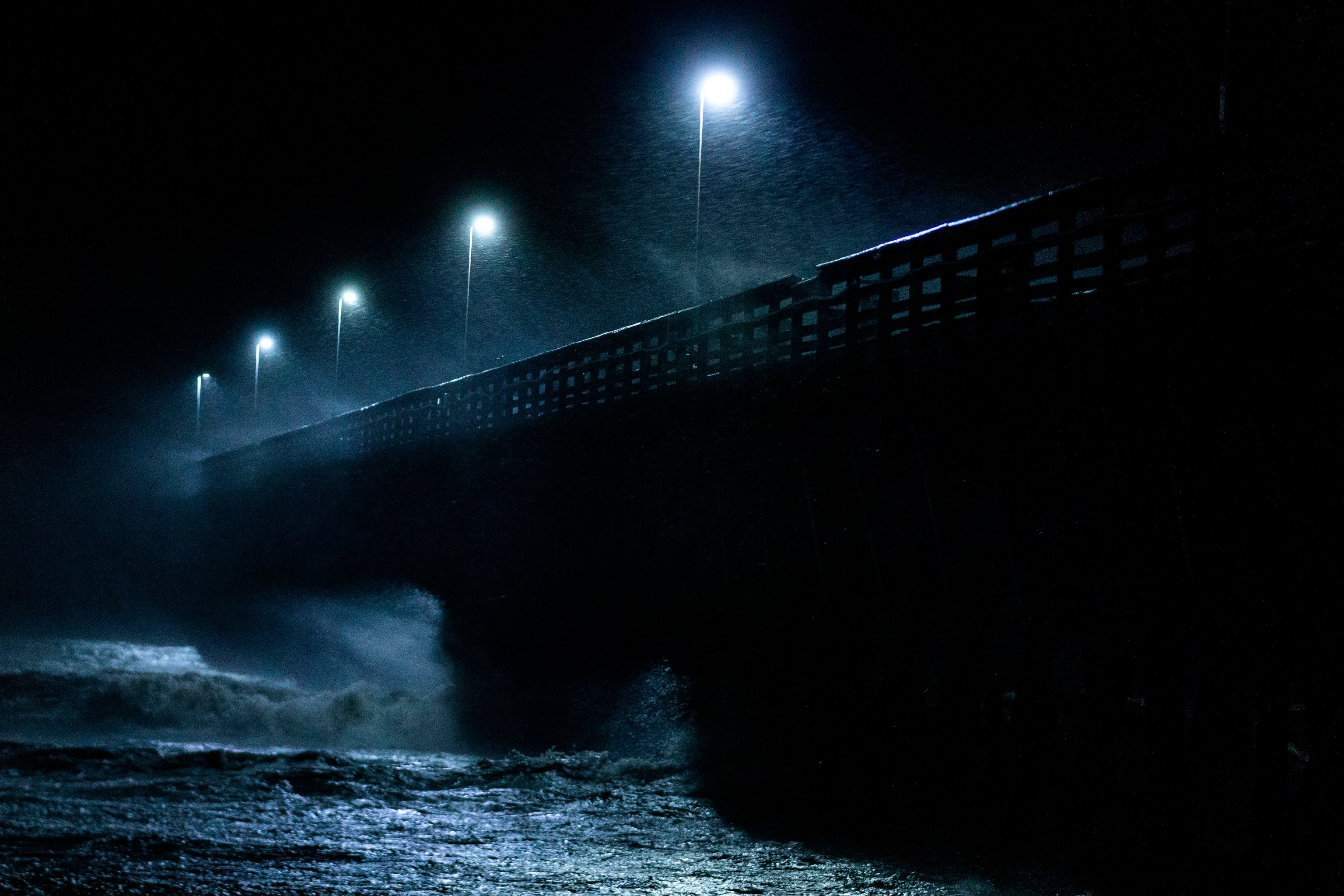 waves crashing into a pier as a hurricane makes landfall