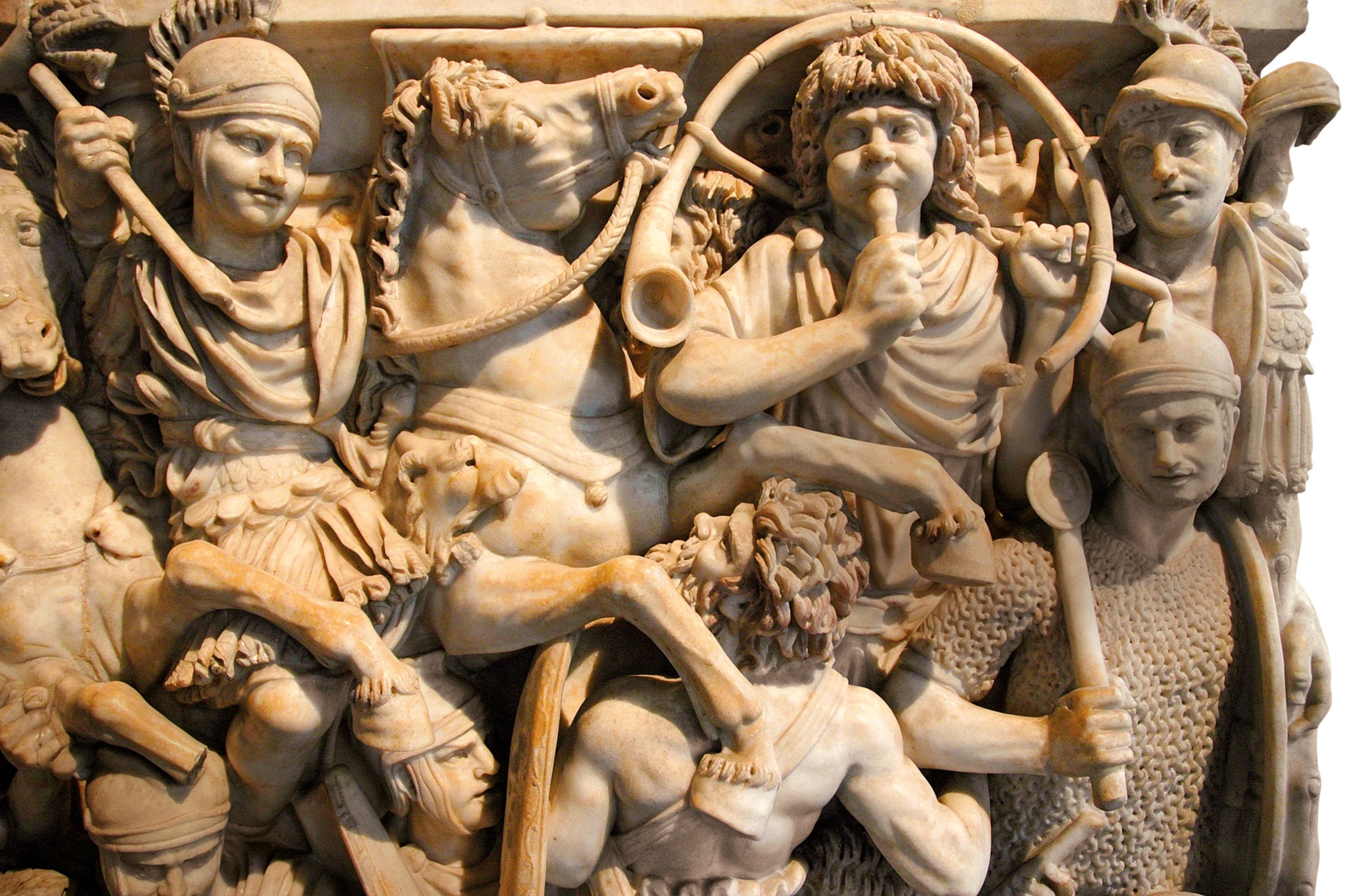 a stone relief of men on horseback and others playing a trumpet
