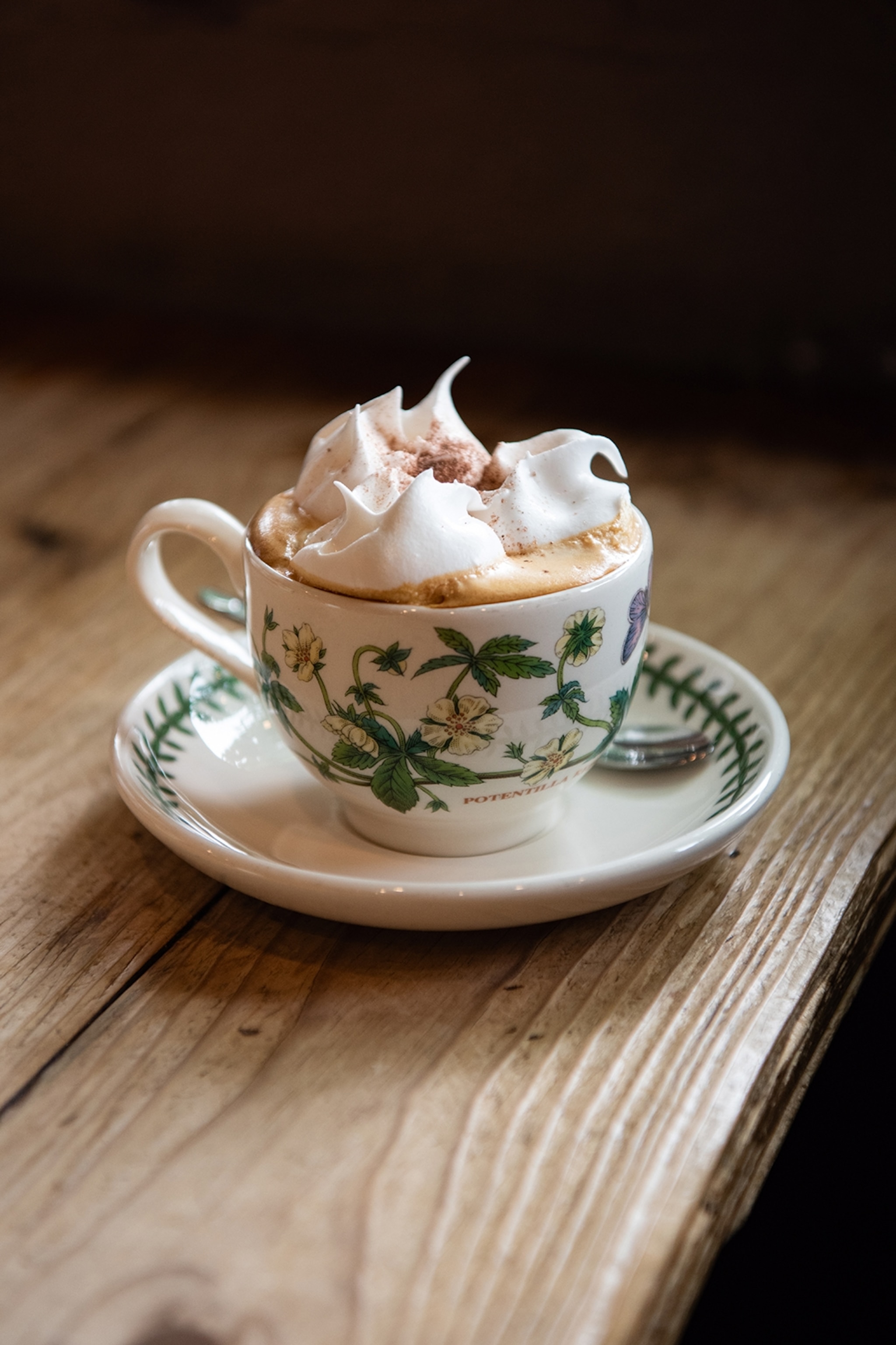 Floral china mug and saucer filled with coffee and topped with cream
