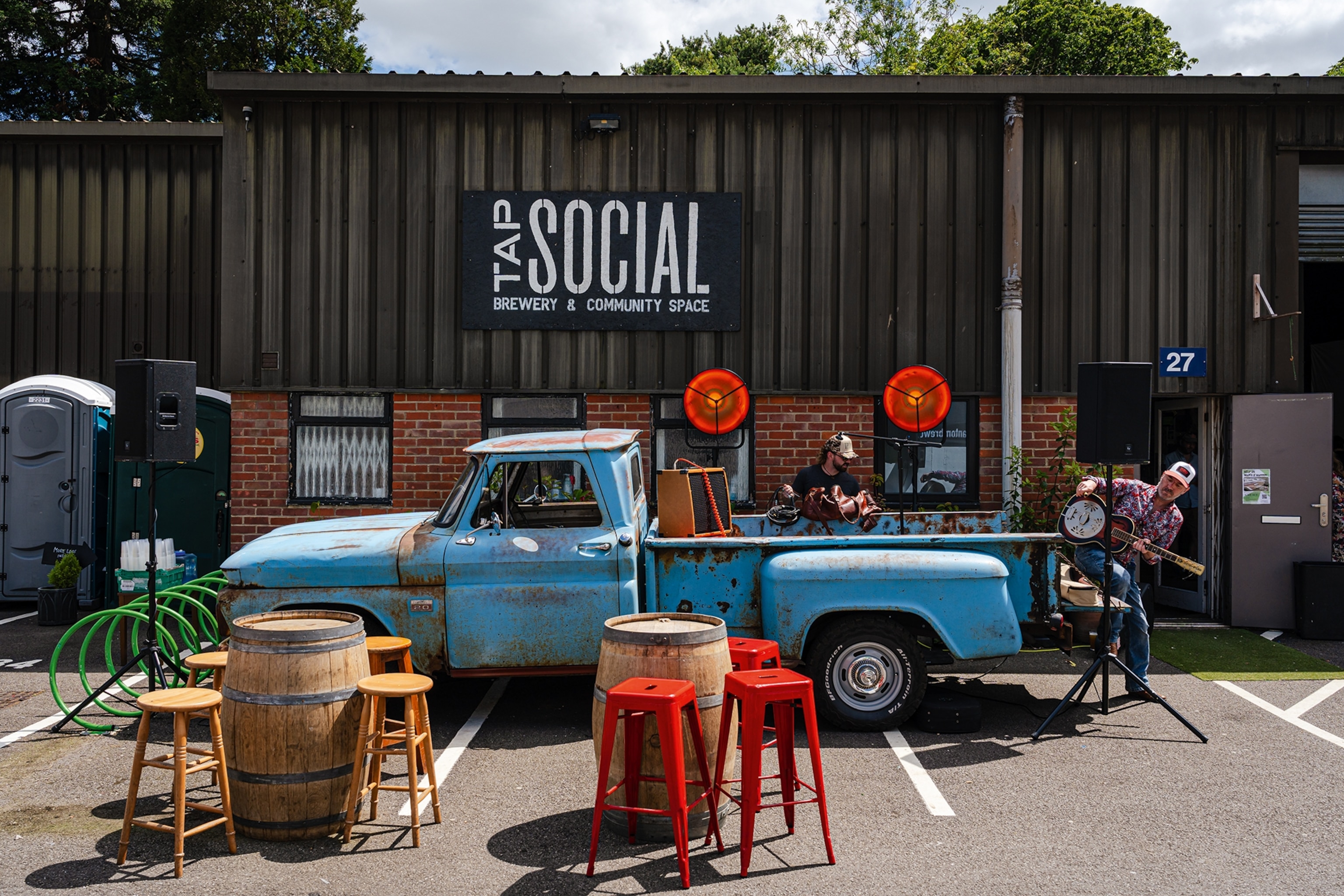 Blue truck parked outside a warehouse with a sign reading Tap Social