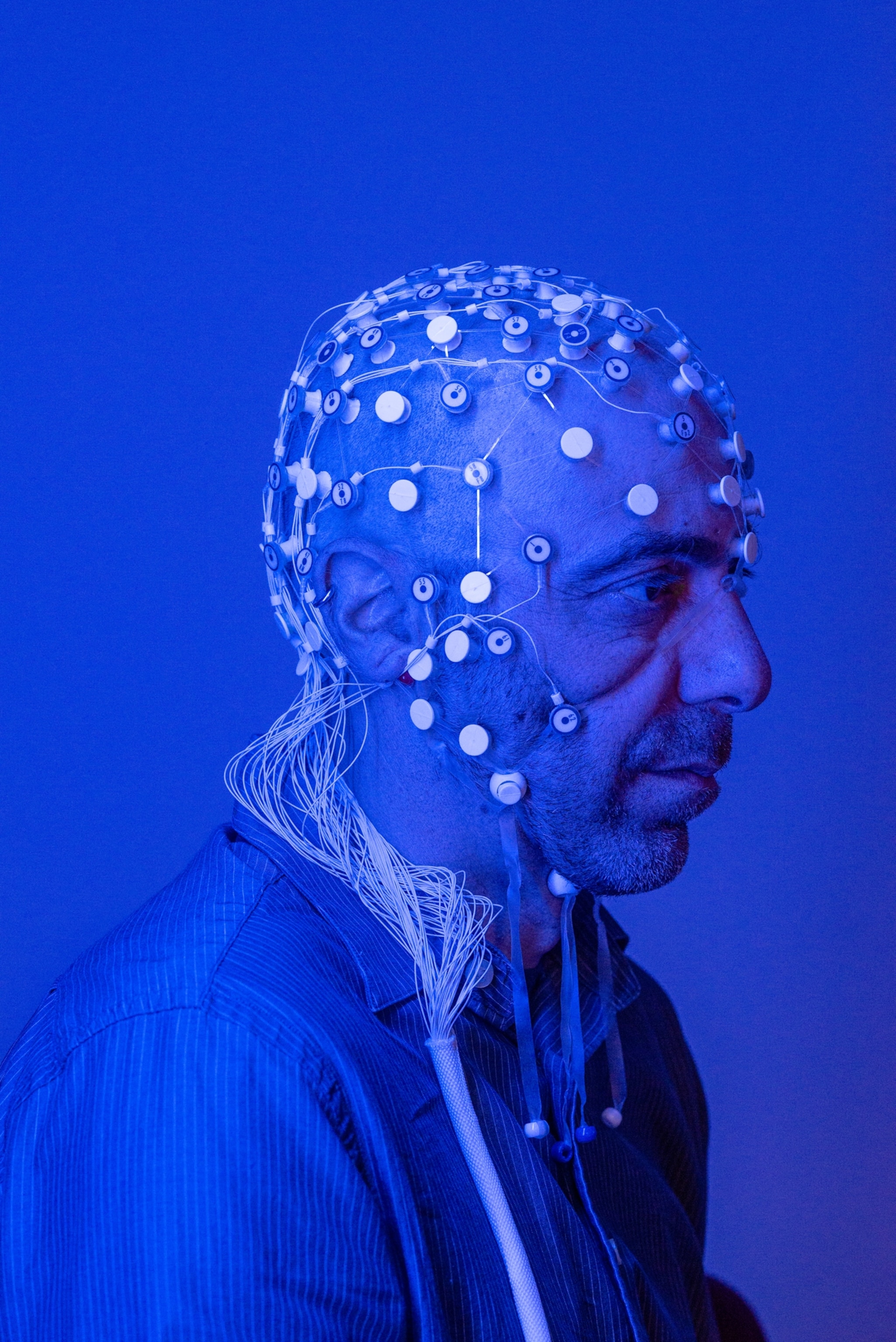 in blue light of a man with sensors attached to his head.