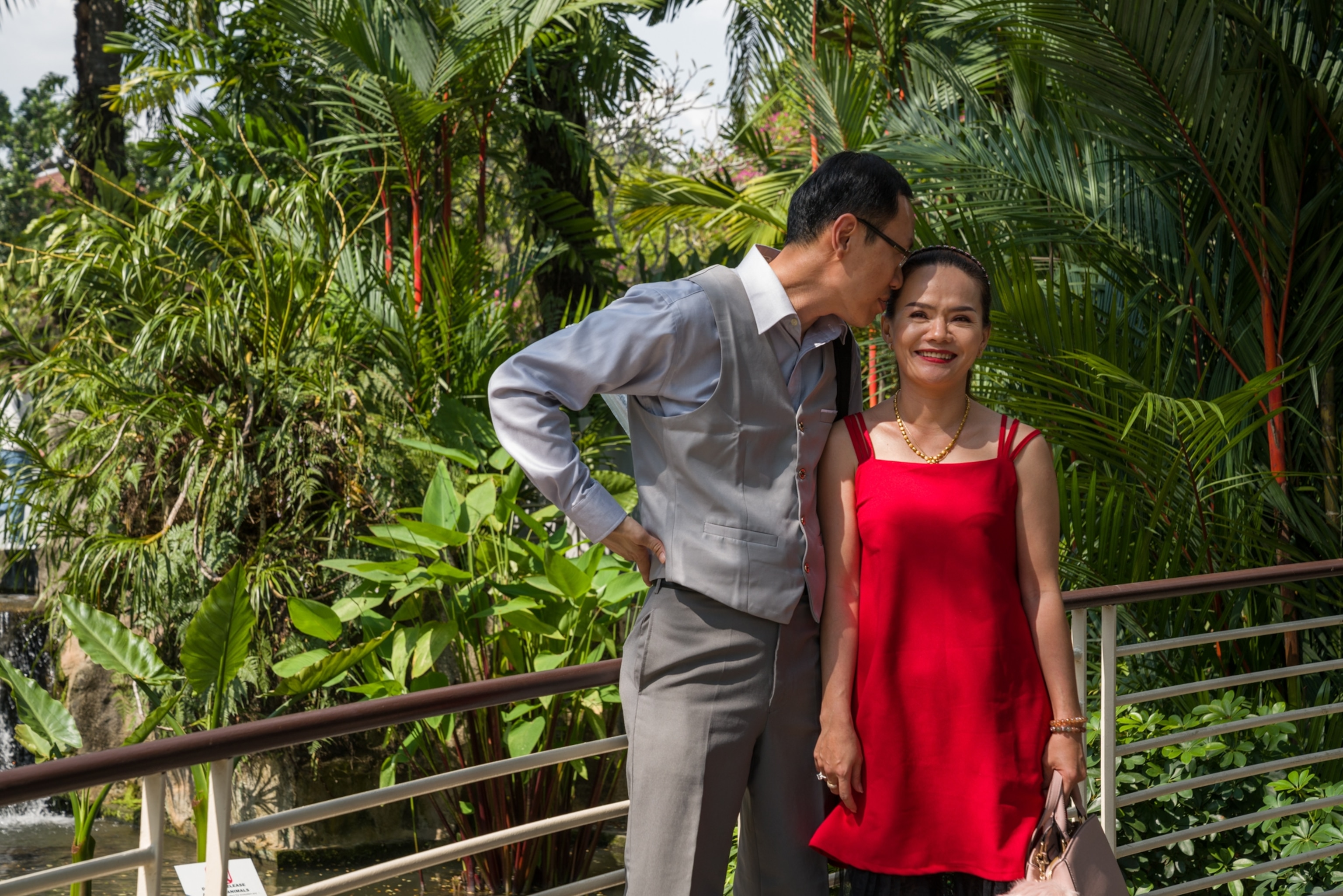 a woman in a red dress standing next to a man with his head to her forehead